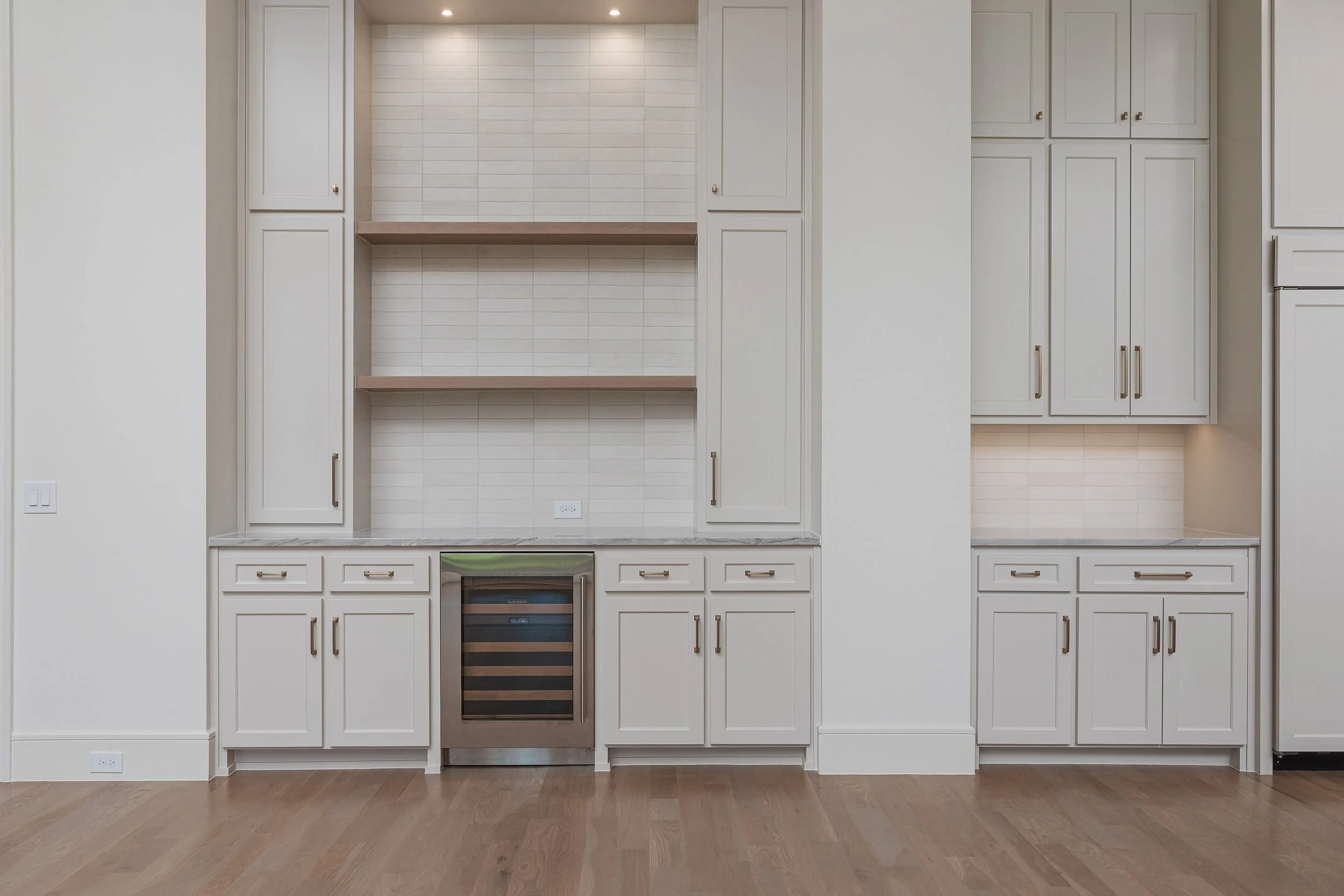 Built-in bar with open shelving, wine refrigerator and paneled cabinetry
