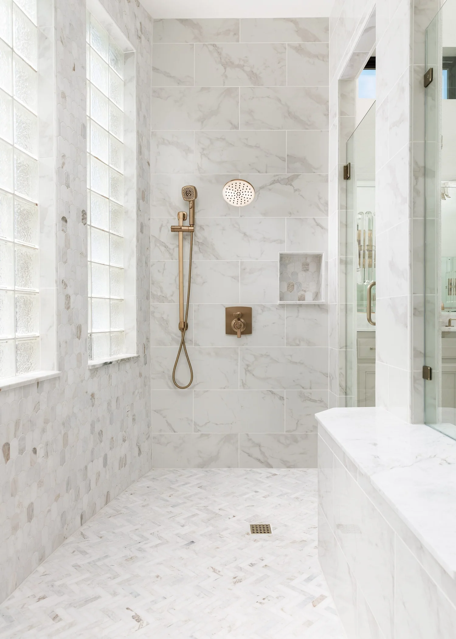 Marble shower with brass fixtures and a glass-block window