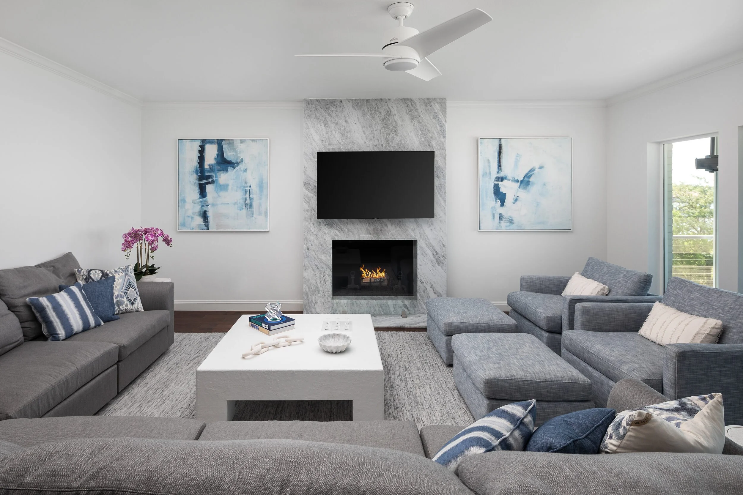 Living room seen from the windows, with a gray sectional, navy pillows and blue abstract art