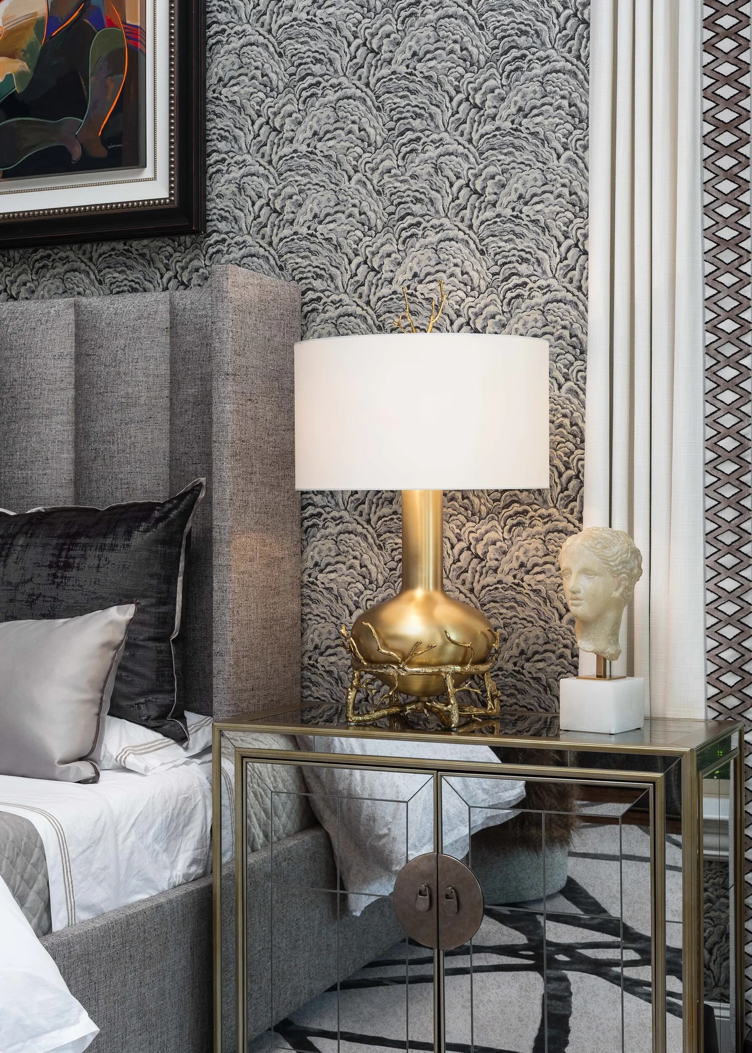 Detail of a brass lamp, sculptural bust and channel-tufted headboard