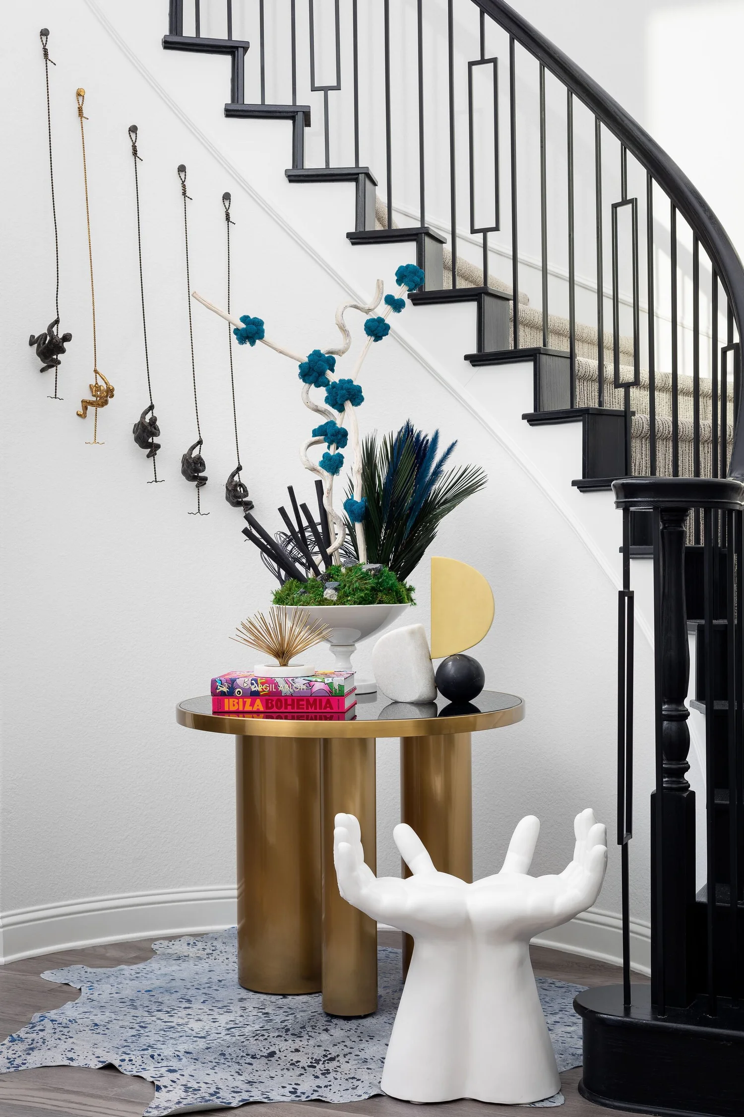 Curved stair with a brass side table and a sculptural hand stool