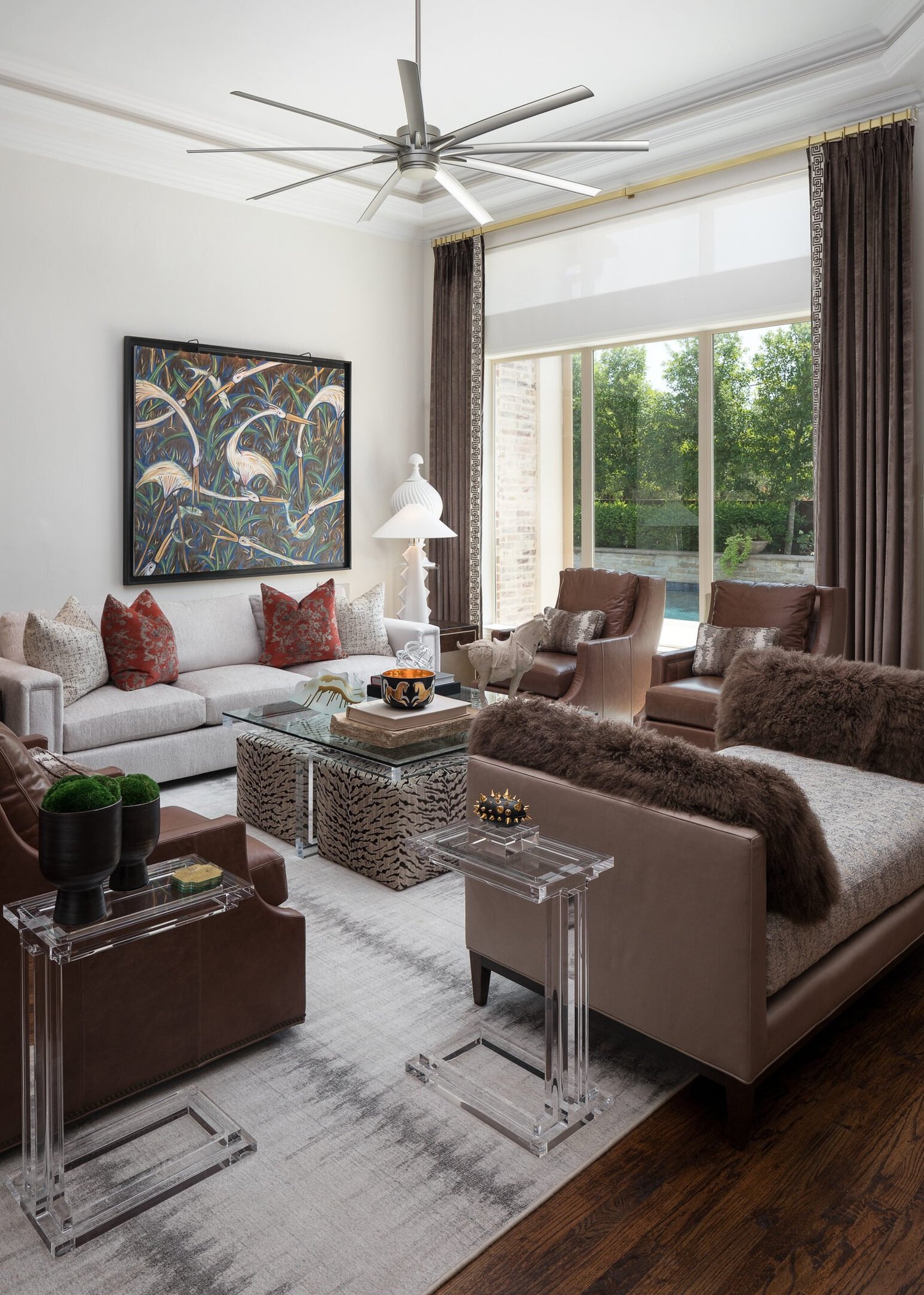 Living room vignette with a leather sofa, patterned ottomans and garden window