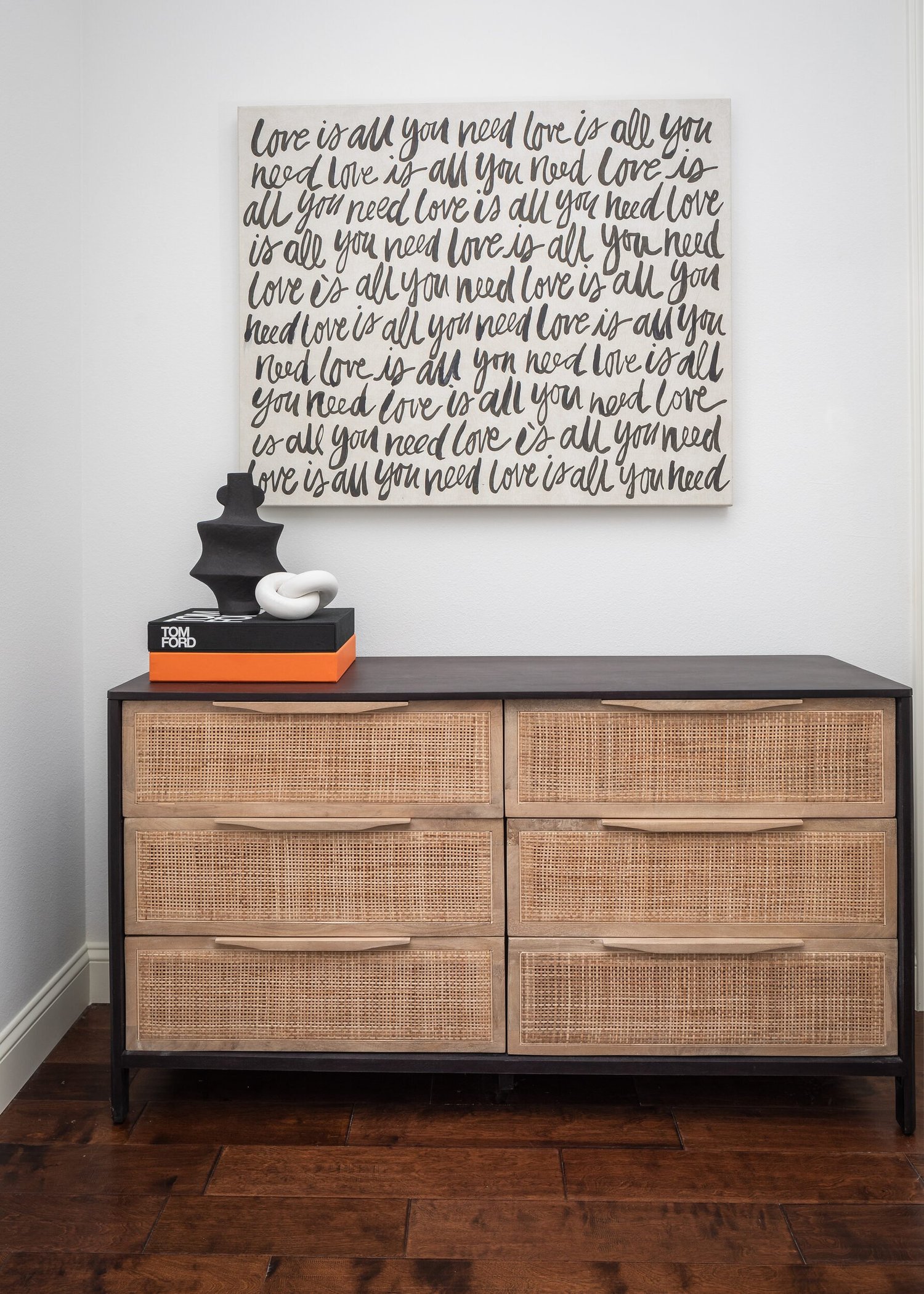 Rattan dresser below hand-lettered art, with black and white accents