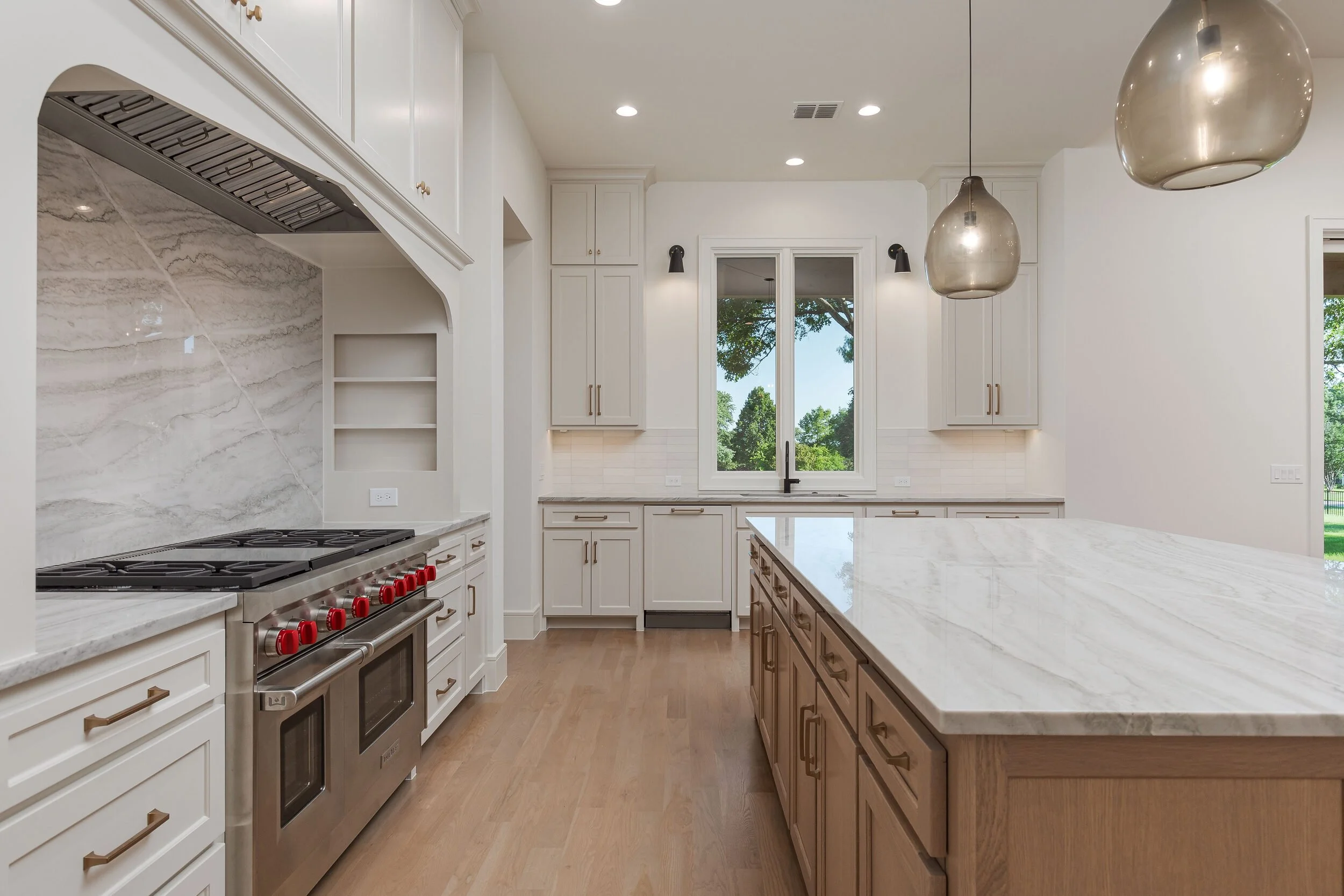 Range wall with a stone backsplash, professional range and marble-topped island