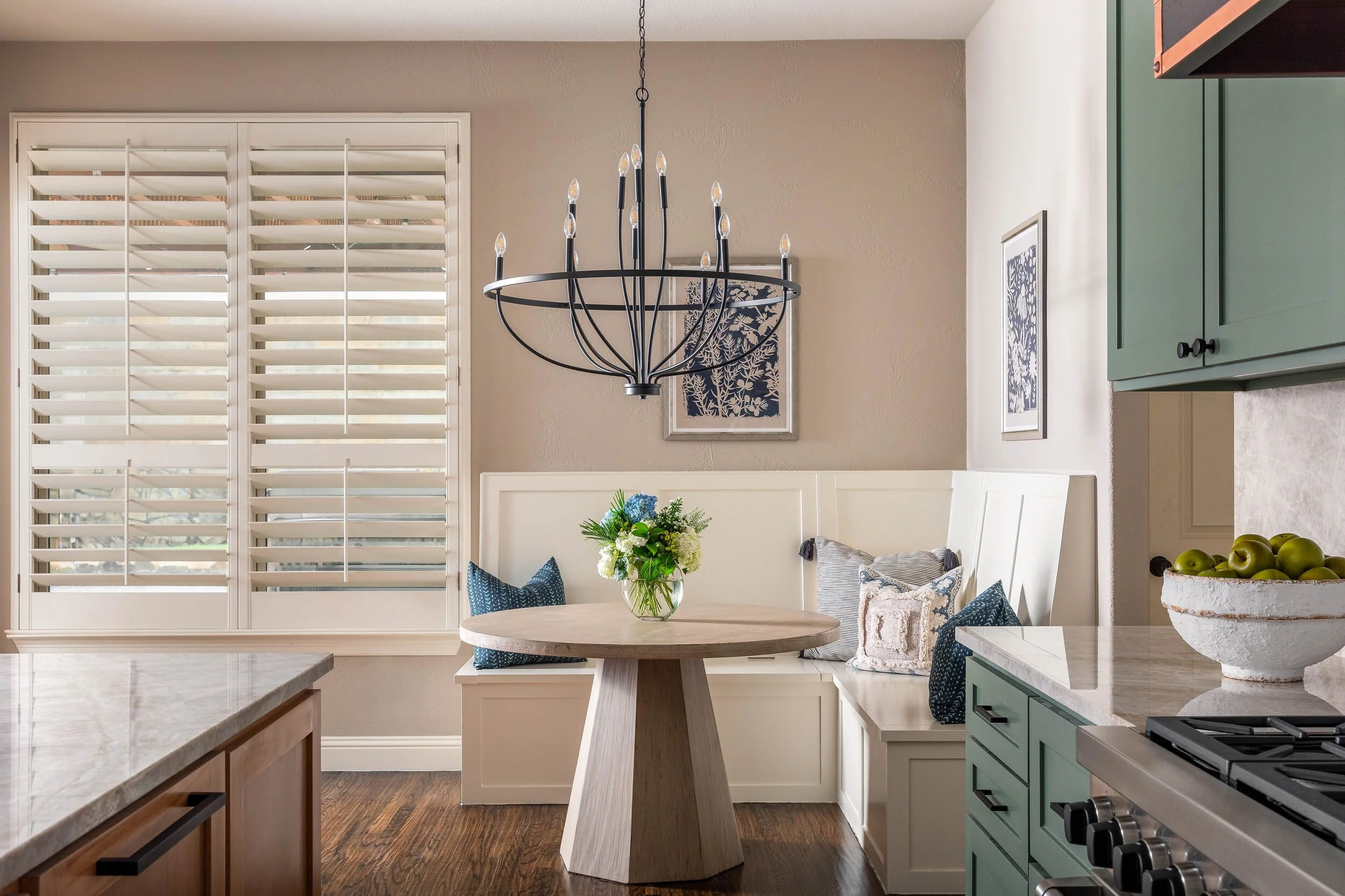 Breakfast room with an iron chandelier, a pedestal table and a built-in banquette