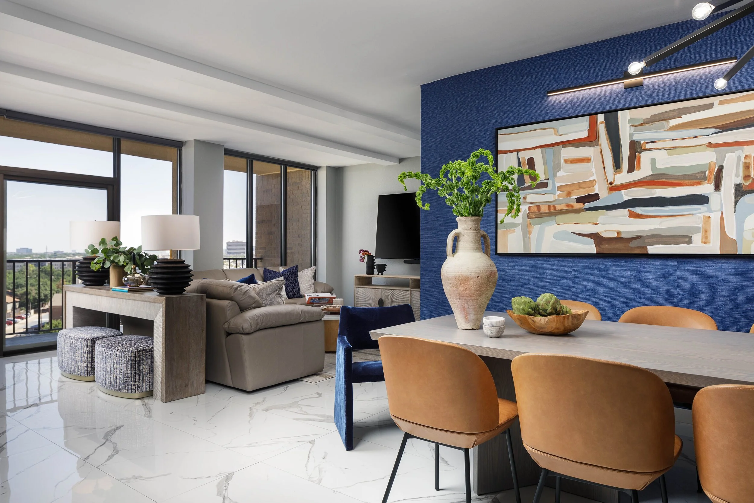 Dining table in the foreground with the living room and high-rise windows behind