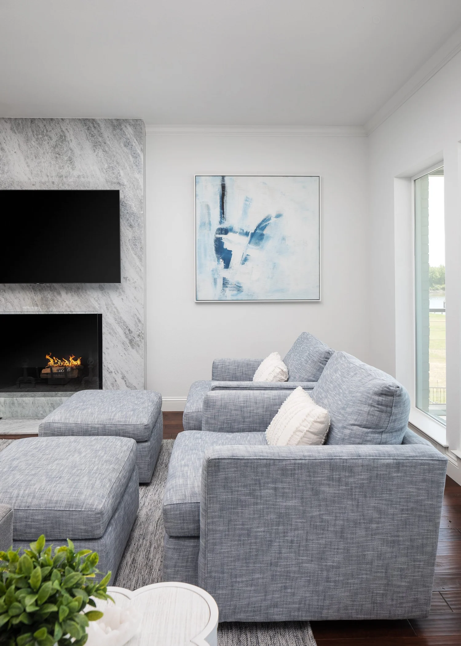 Gray swivel chairs beside the marble fireplace and a window to the lake