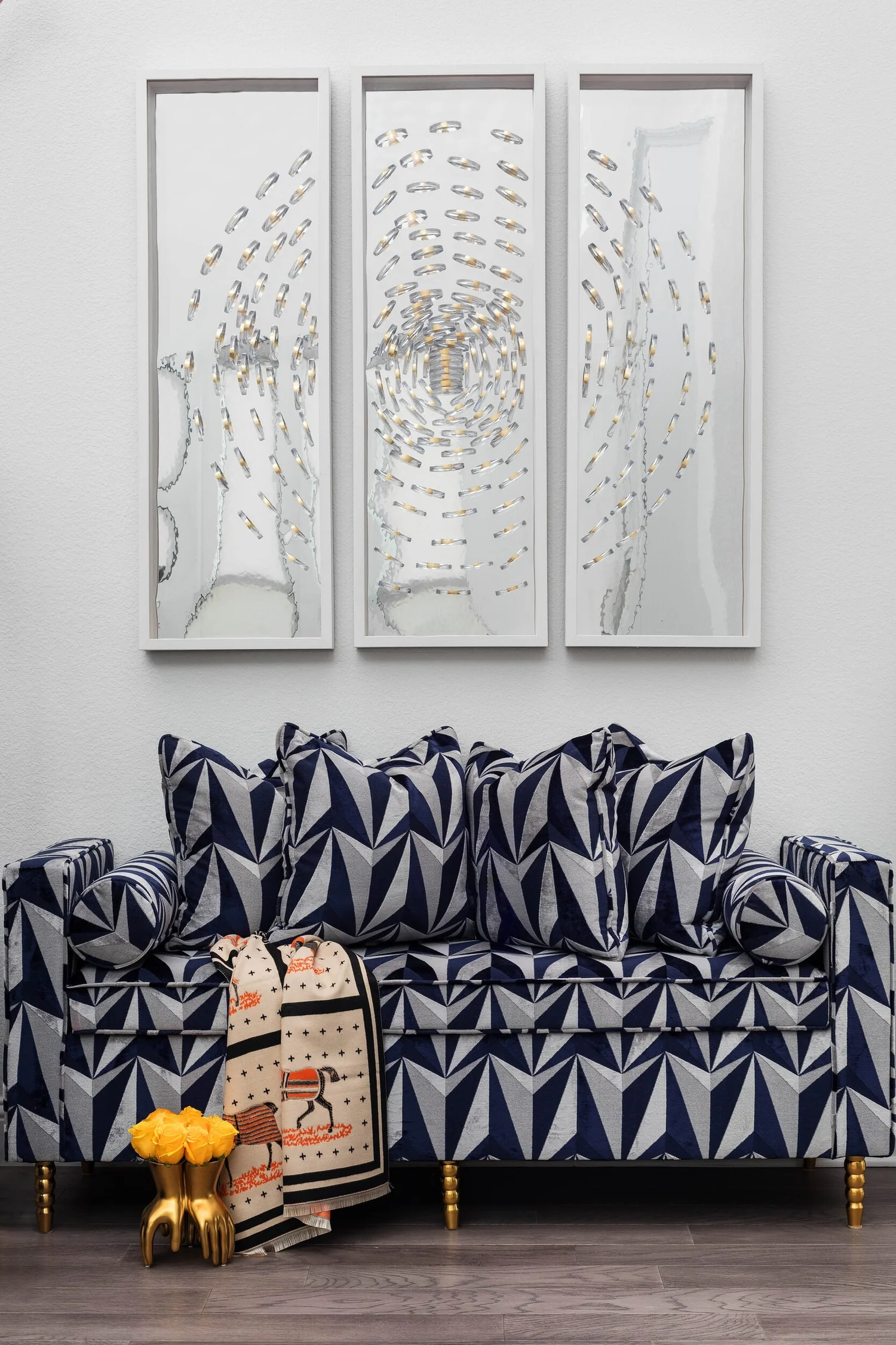 Navy and white patterned settee beneath a framed triptych