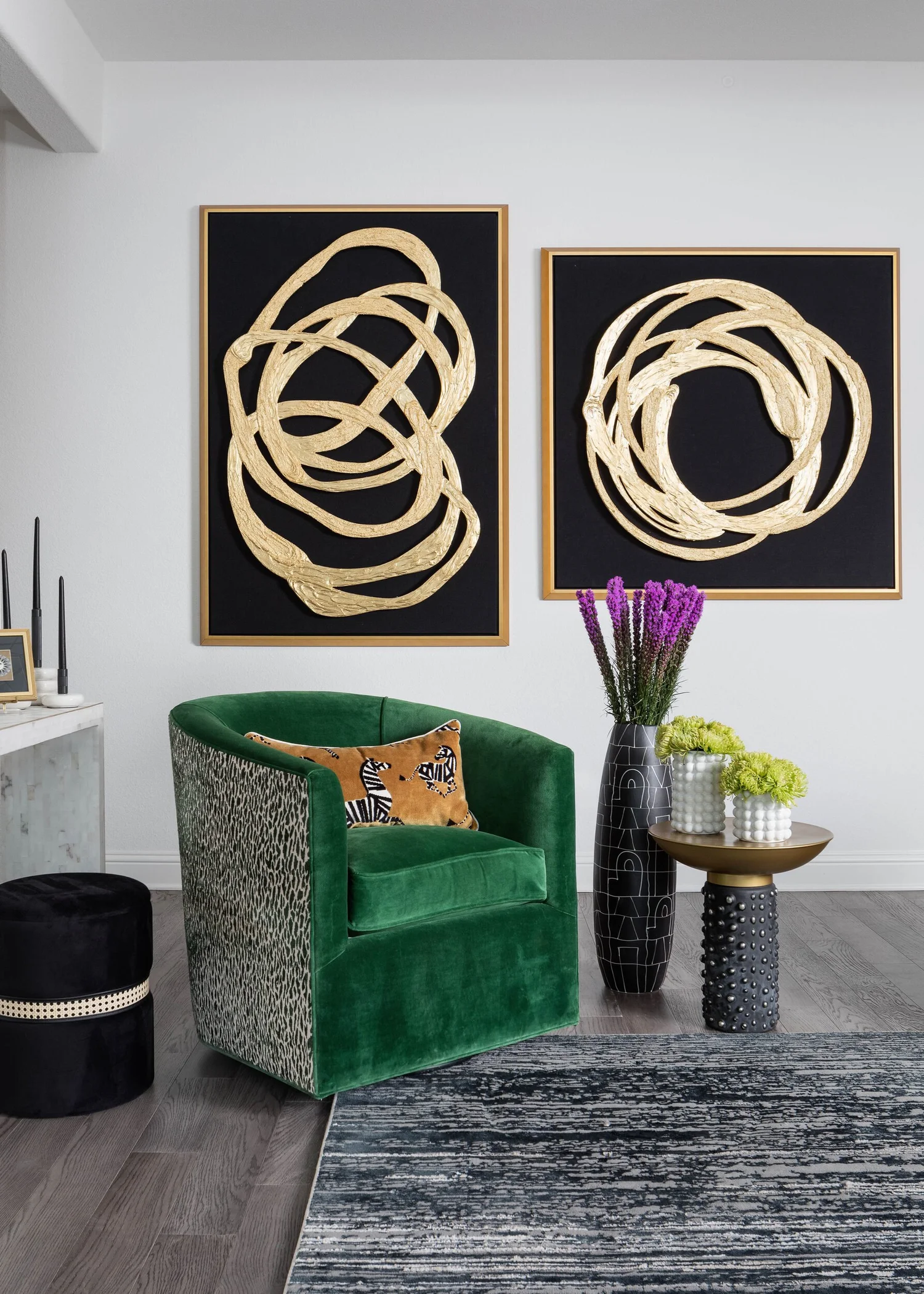 Green velvet swivel chair beneath a pair of black and gold abstract artworks