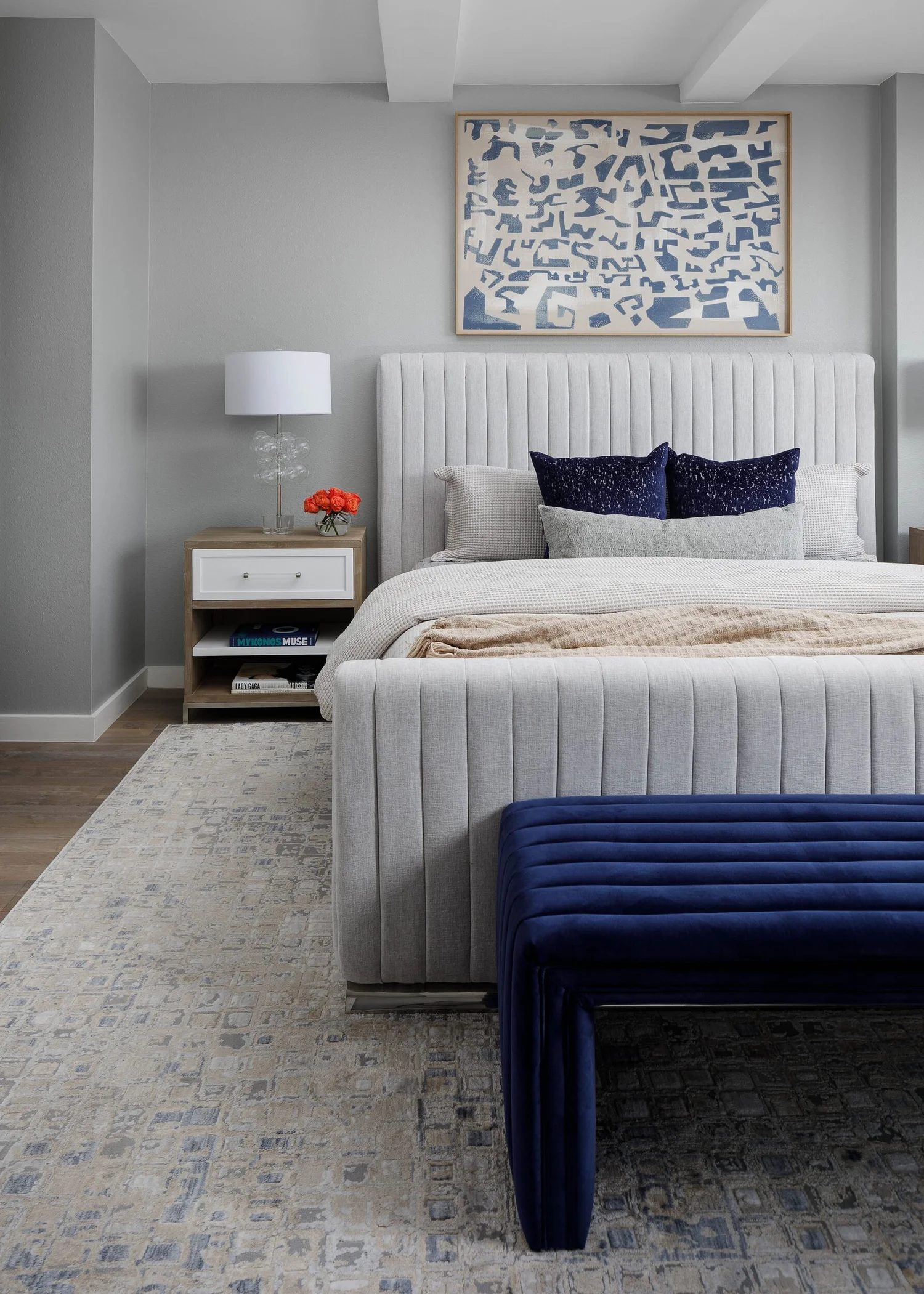 Channel-tufted bed and navy velvet bench on a patterned rug
