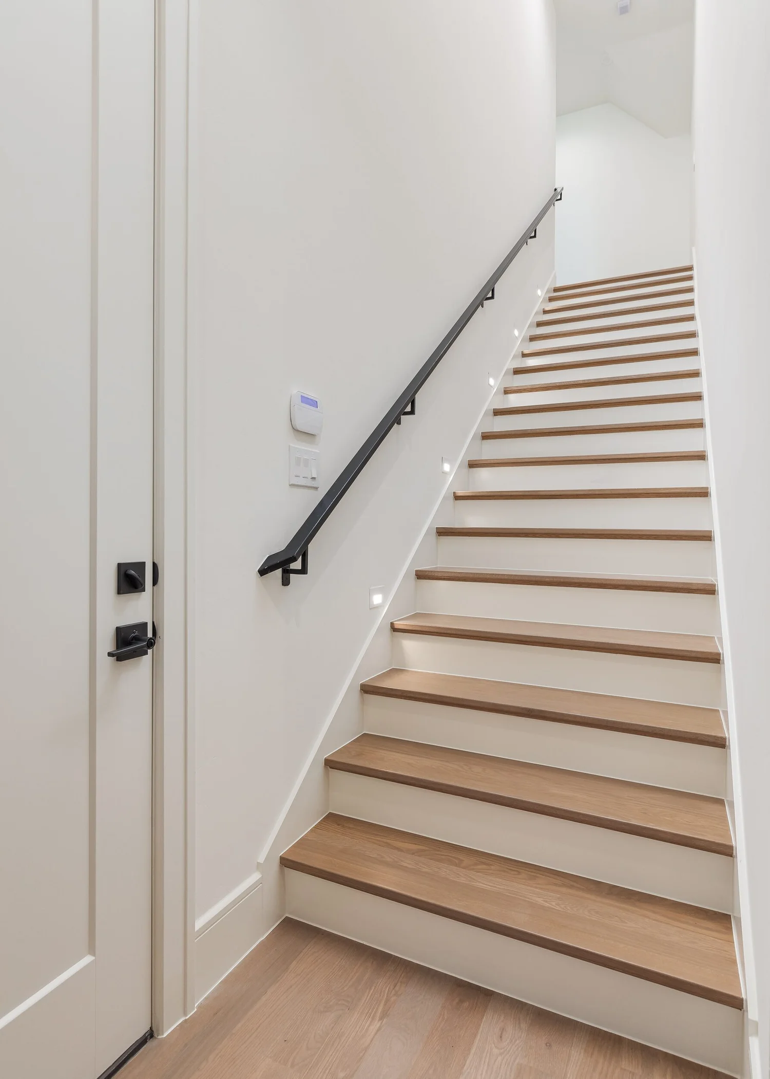 Staircase with white oak treads and a black metal handrail