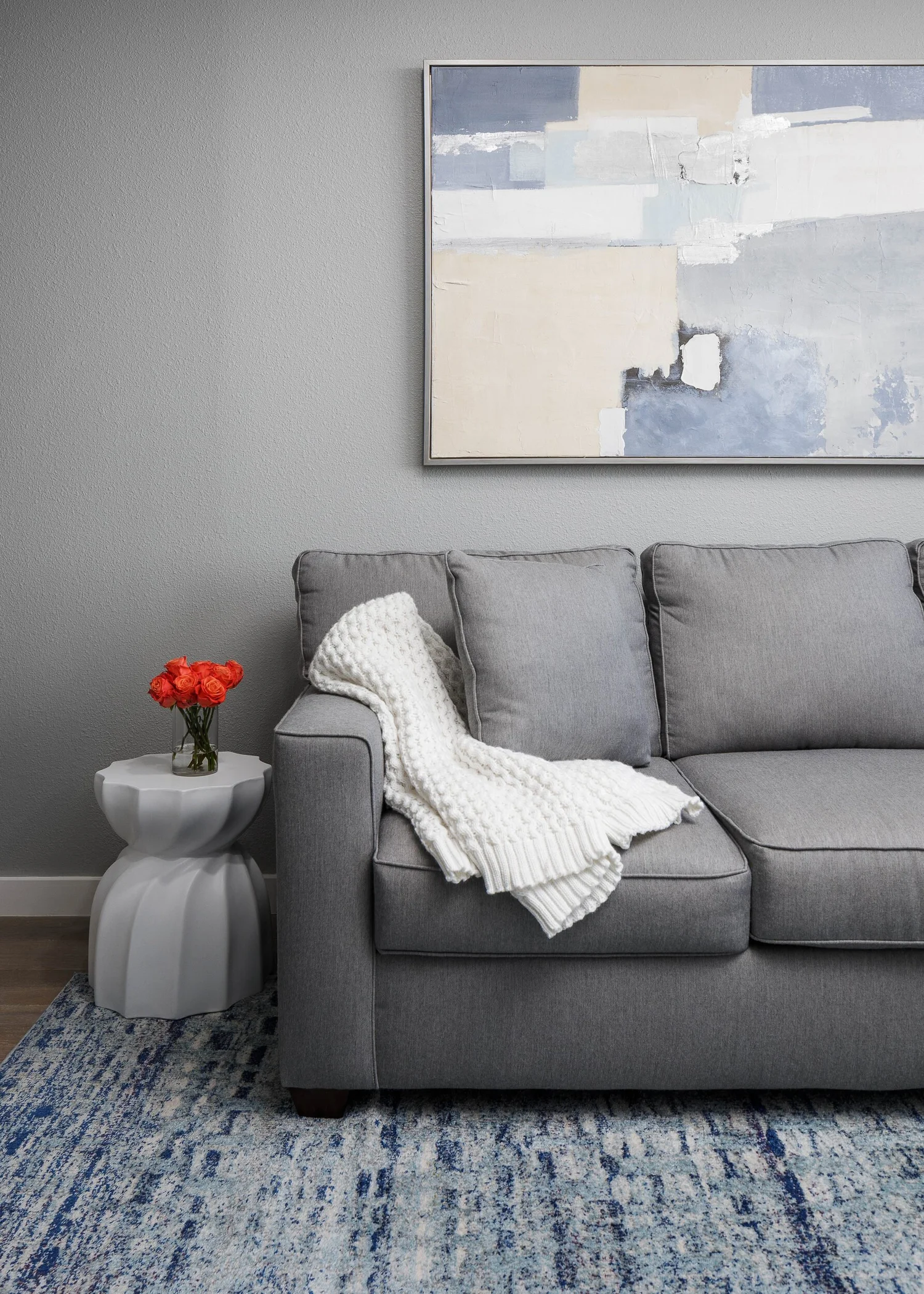 Gray sofa with a knit throw below a soft abstract painting
