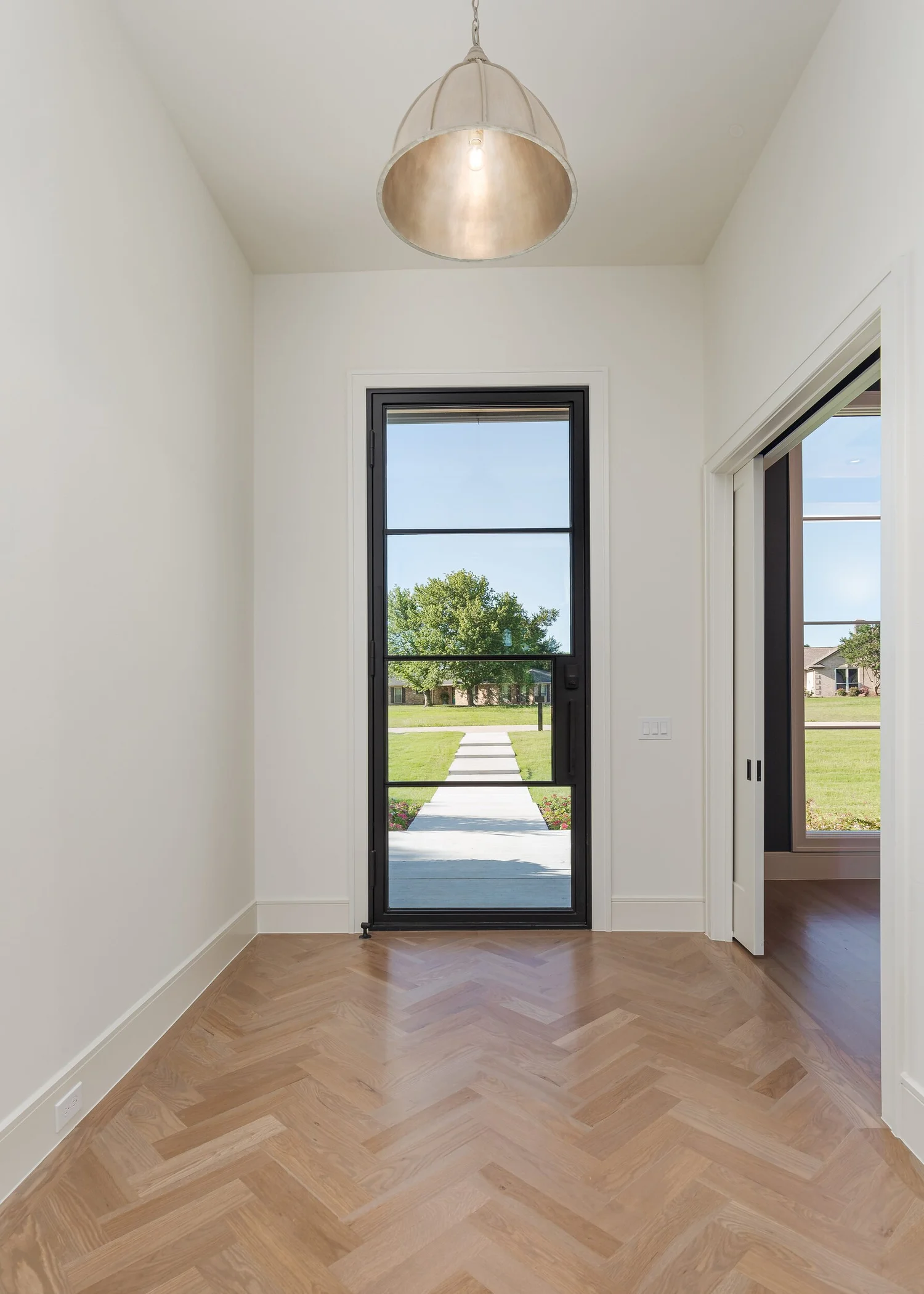 Entry hall with herringbone white oak floors and a black steel front door