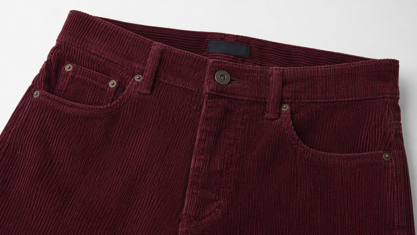 Close-up of burgundy corduroy fabric and five-pocket trouser construction detail for casual bottoms manufacturing
