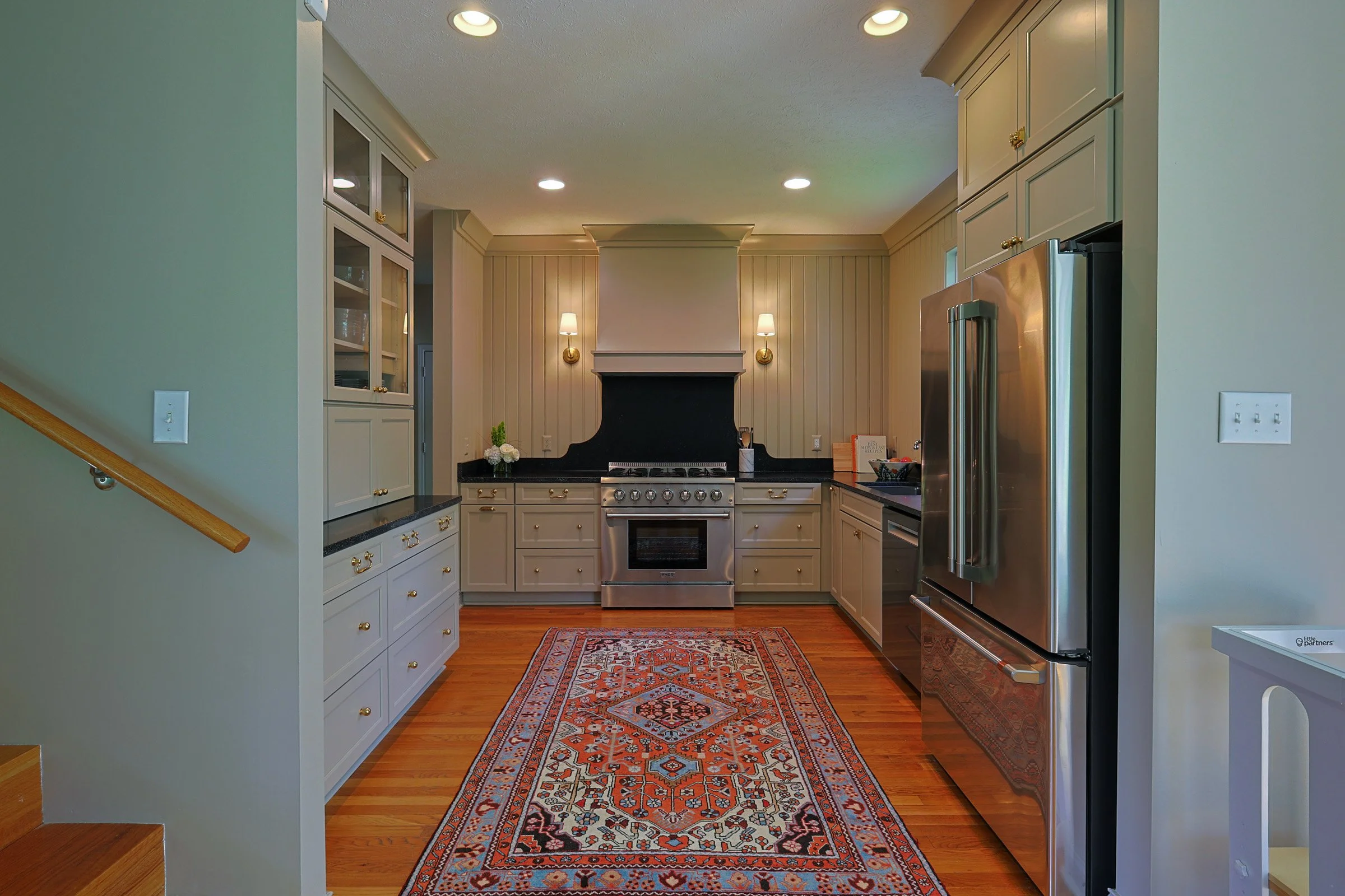 Remodeled kitchen with white cabinets, custom range hood, and quartz counters in a Carmel home