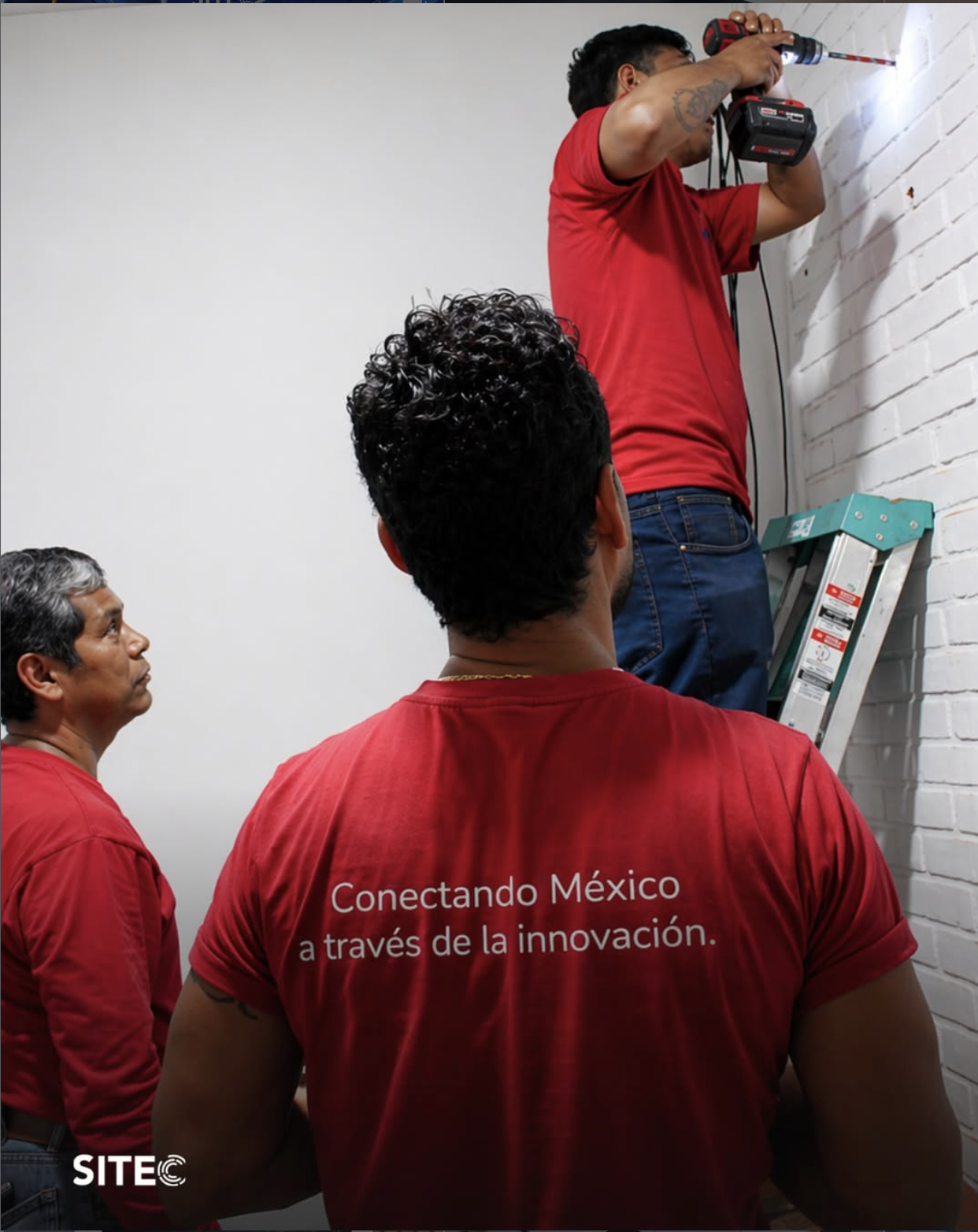 Equipo con camisetas rojas de SITEC trabajando en una instalación interior.