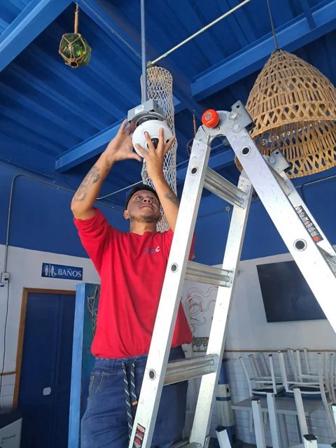 Técnico sobre una escalera trabajando en el techo de El Pecadito.