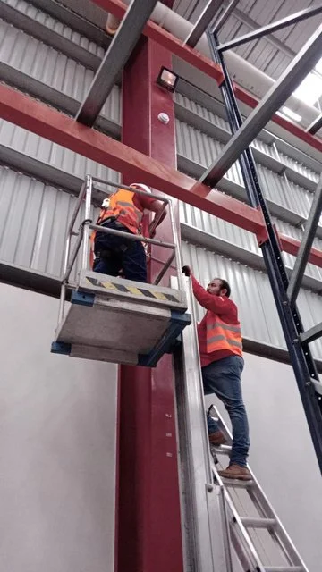 Técnicos trabajando con una plataforma elevadora junto a la estructura de CEDIS Sanctorum.