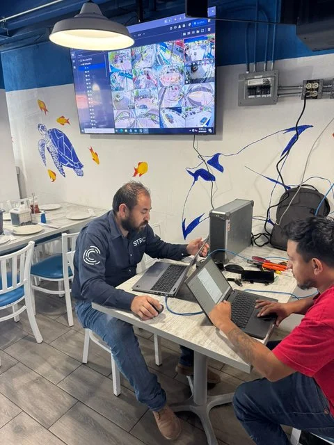 Equipo de trabajo junto a una computadora y un monitor de videovigilancia en El Pecadito.