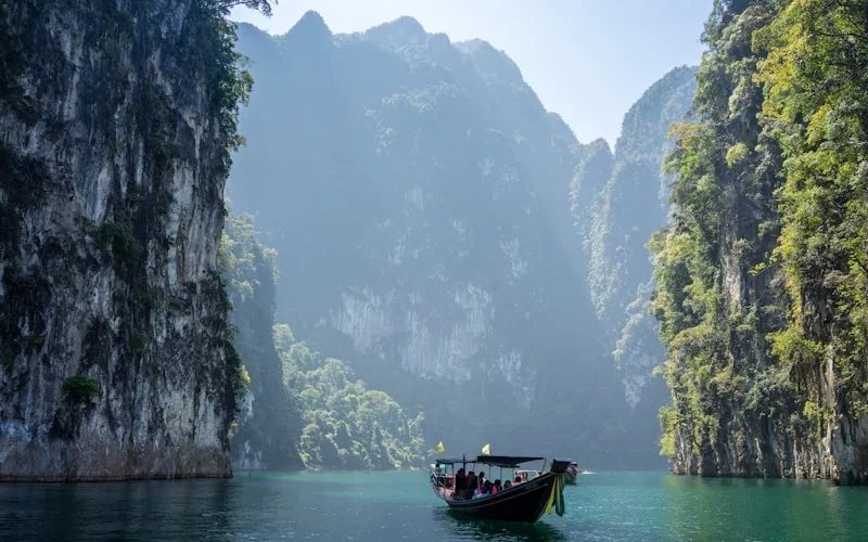 Longtail boat navigating through dramatic limestone cliffs in Krabi, Thailand