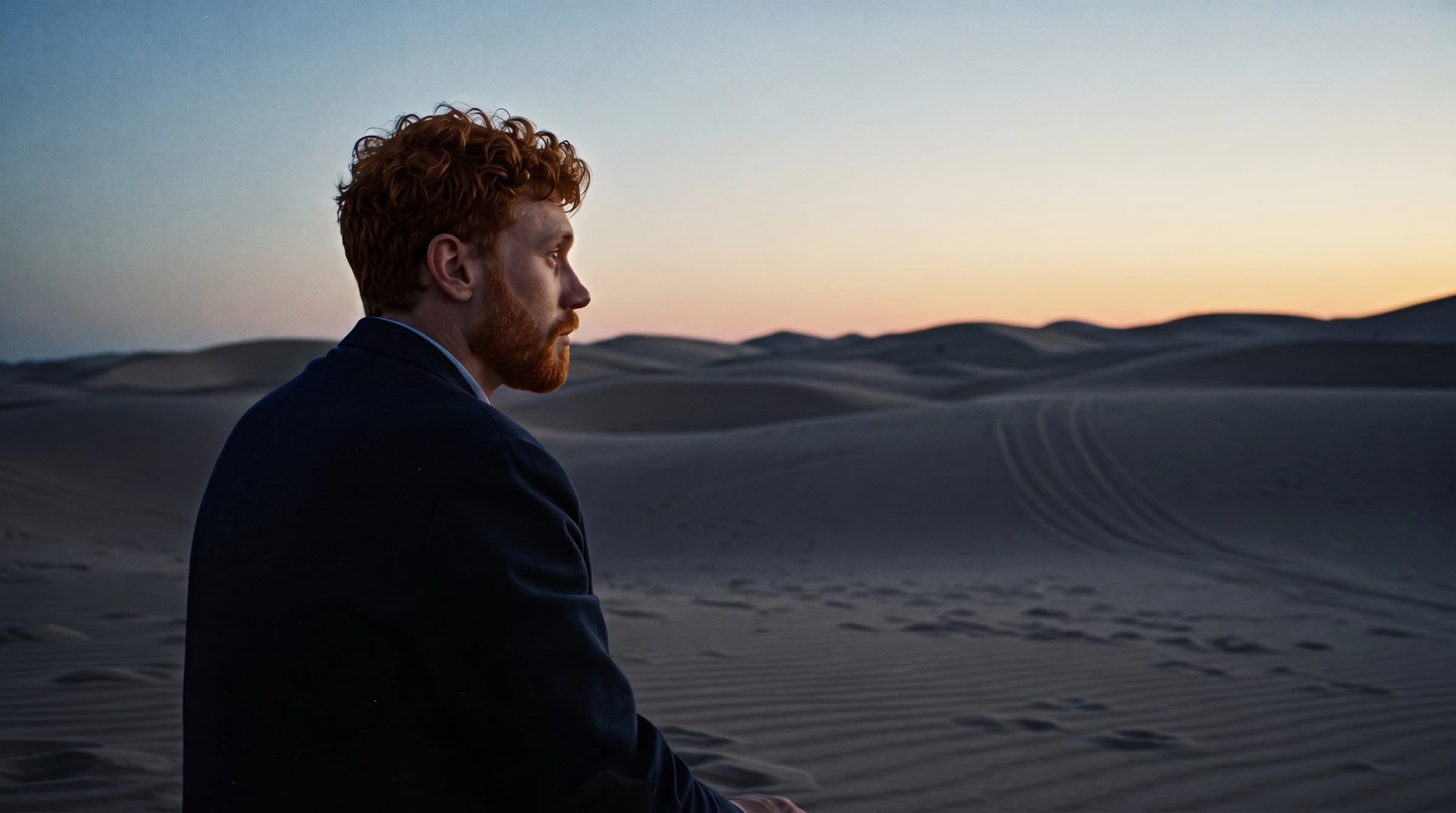 Stuart, bearded, looks out over the dunes at dusk