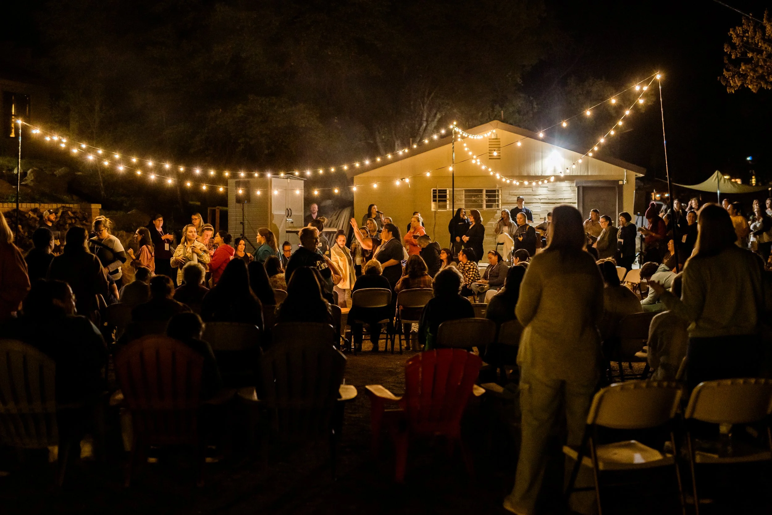 Women gathered around the fire pit under string lights