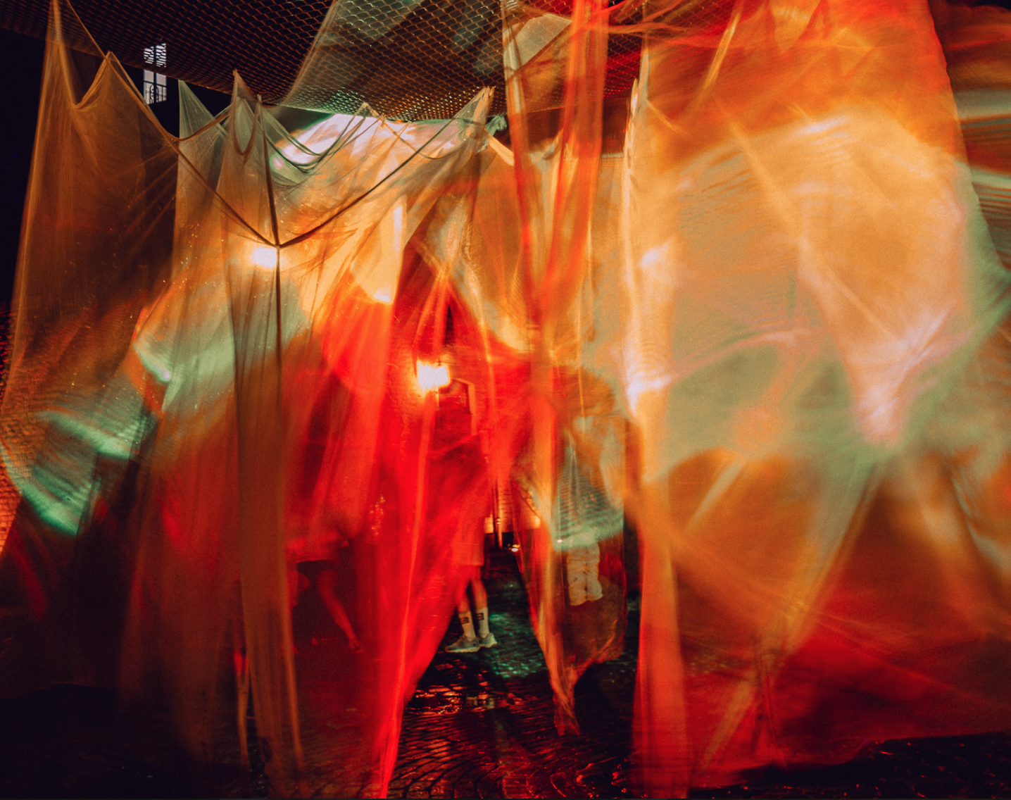 Northern Light 2025: orange and green laser light through layers of fabric