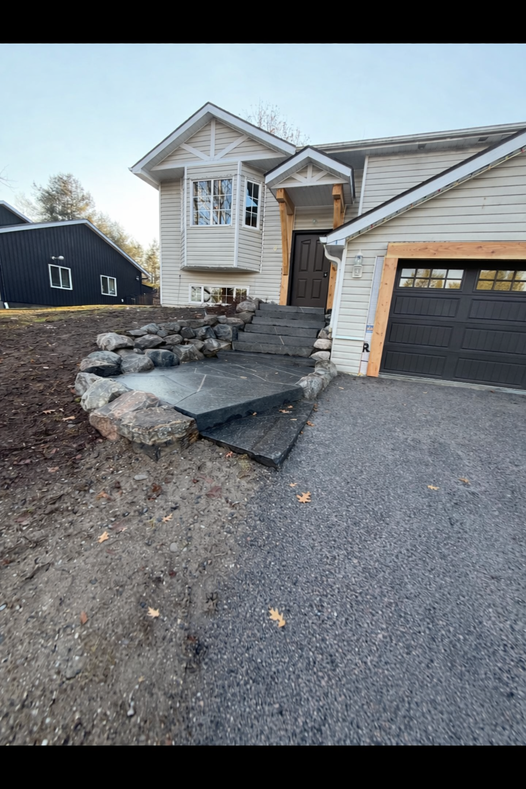 Hardscape project after construction: stone staircase, patio, boulder retaining wall, and driveway