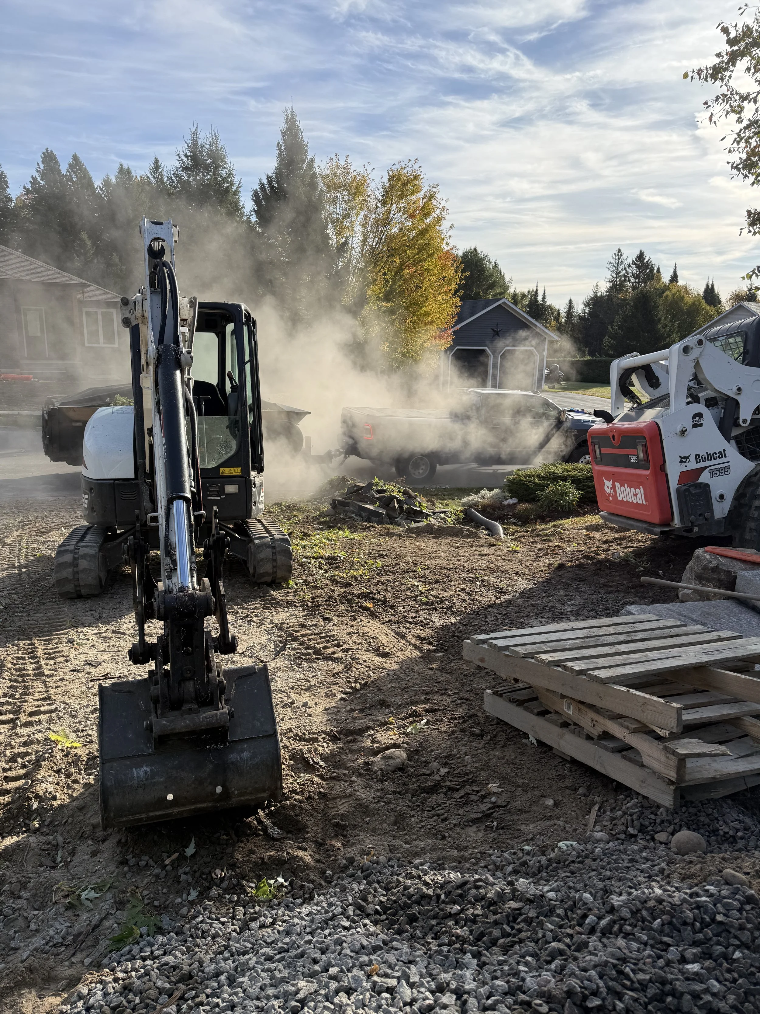 Hardscape site with excavation equipment and dump trailer
