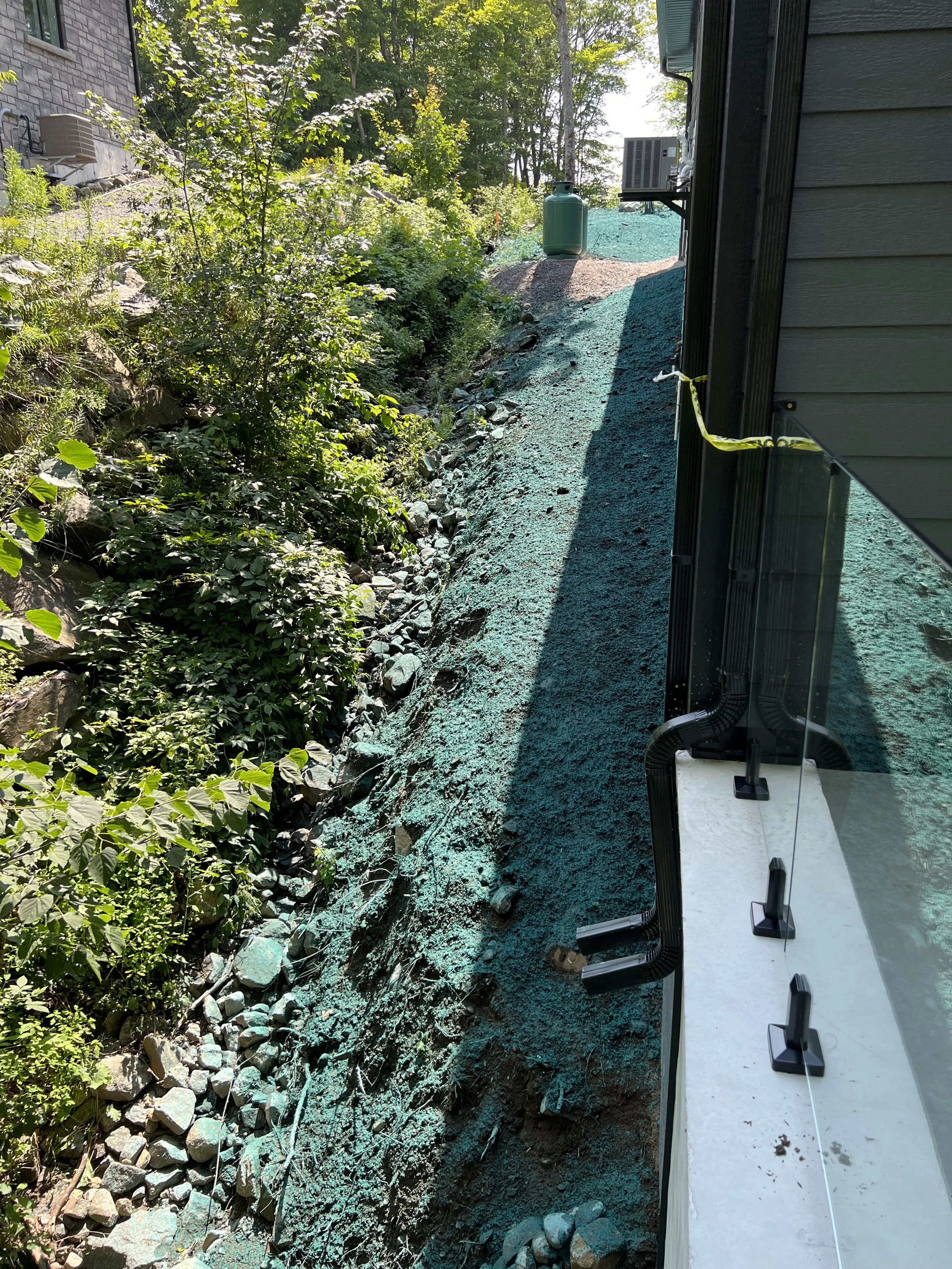 Hydroseeding applied after backfill against a house in Muskoka
