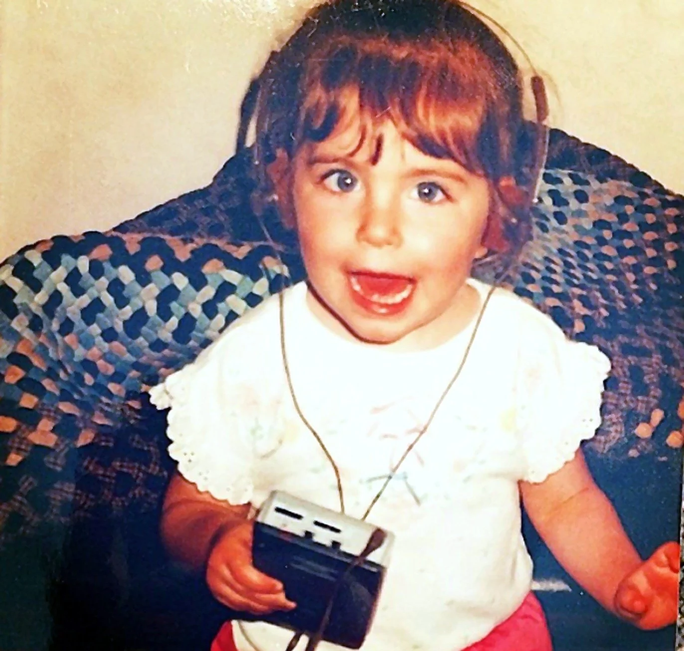 Christina as a toddler in headphones, holding a cassette player and mid-song