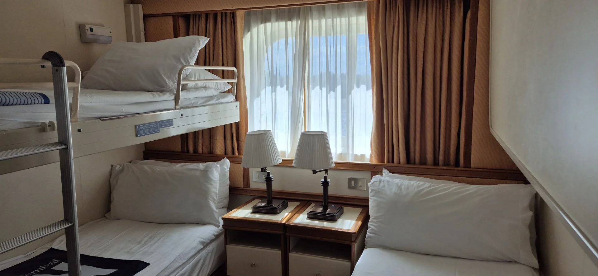 Beds and window inside a cruise ship cabin.