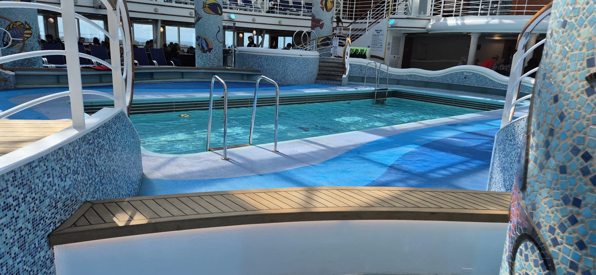 Indoor cruise ship pool surrounded by mosaic columns.