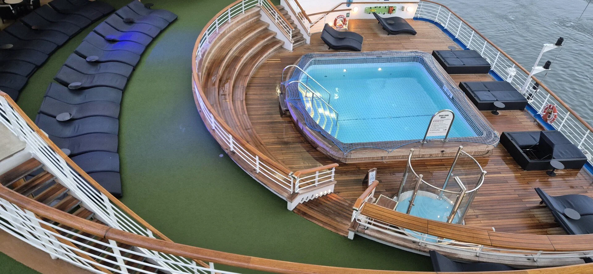 Cruise ship pool and surrounding deck viewed from above.