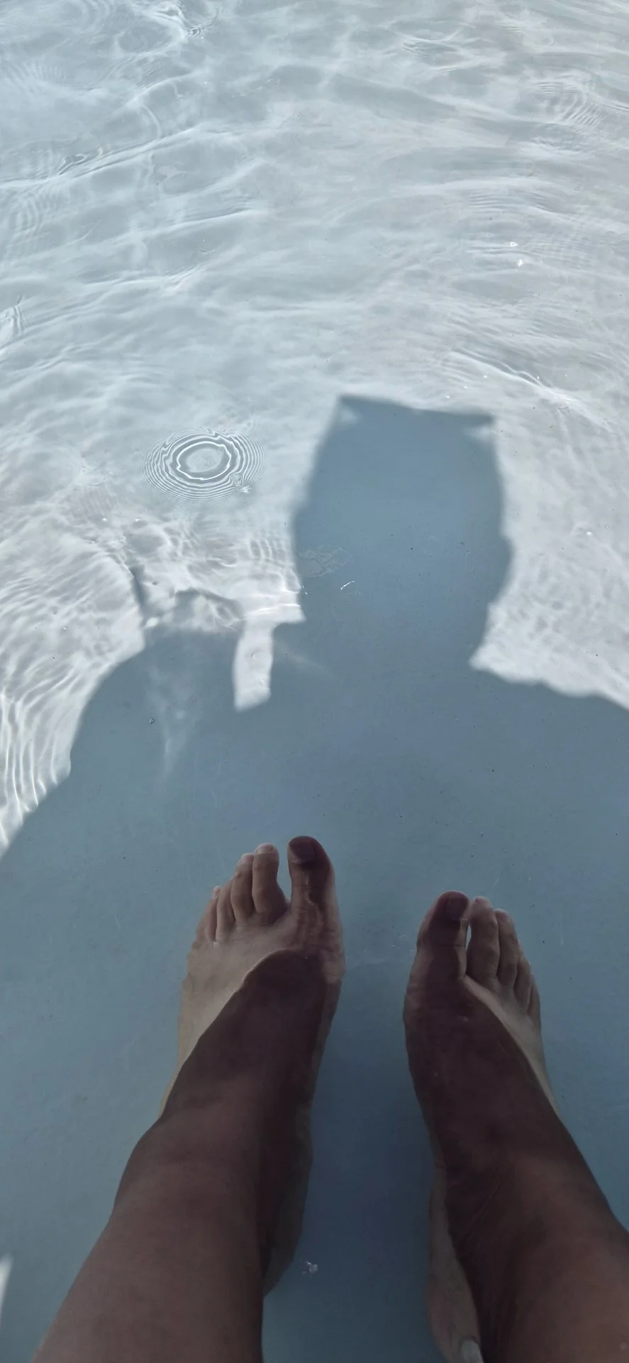 Feet resting in shallow pool water.