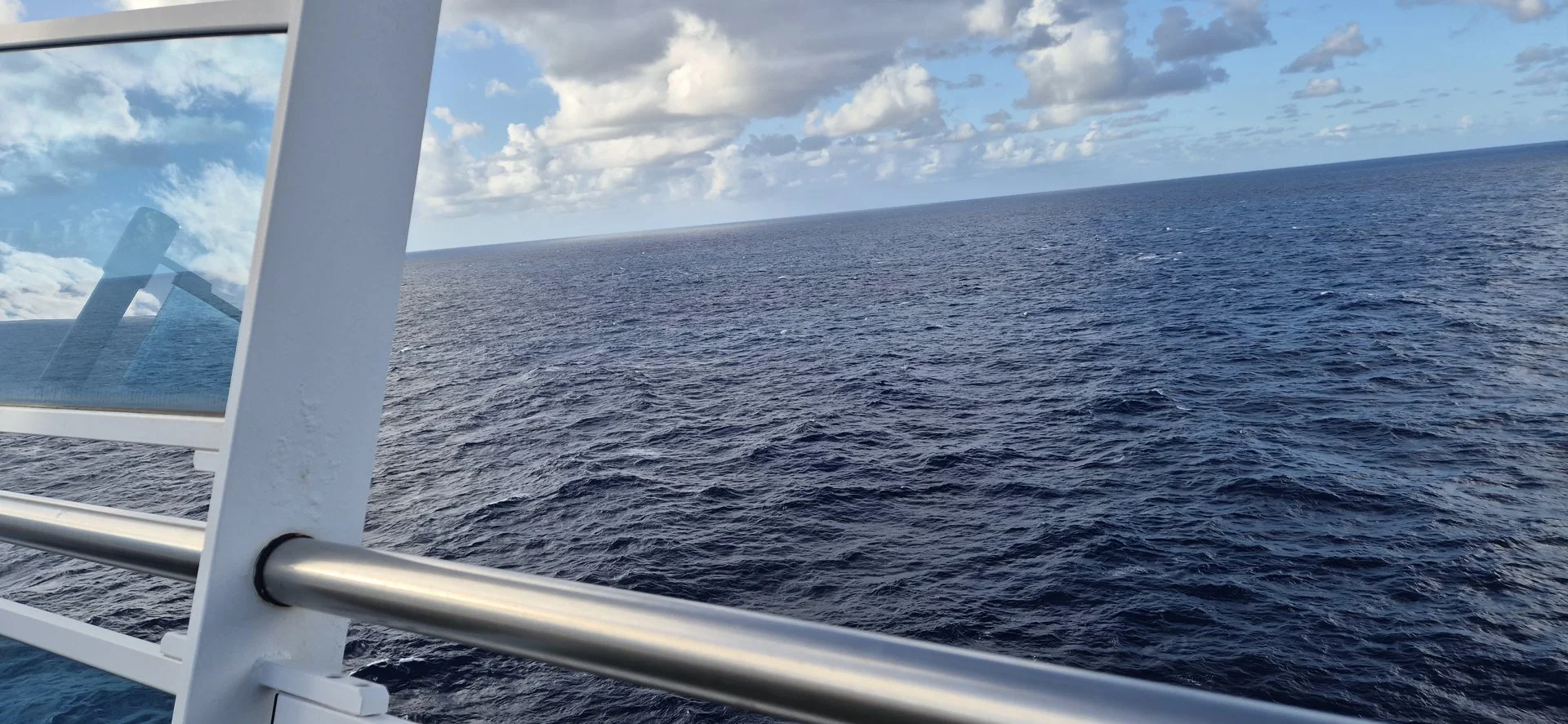 Open ocean viewed over a cruise ship railing.