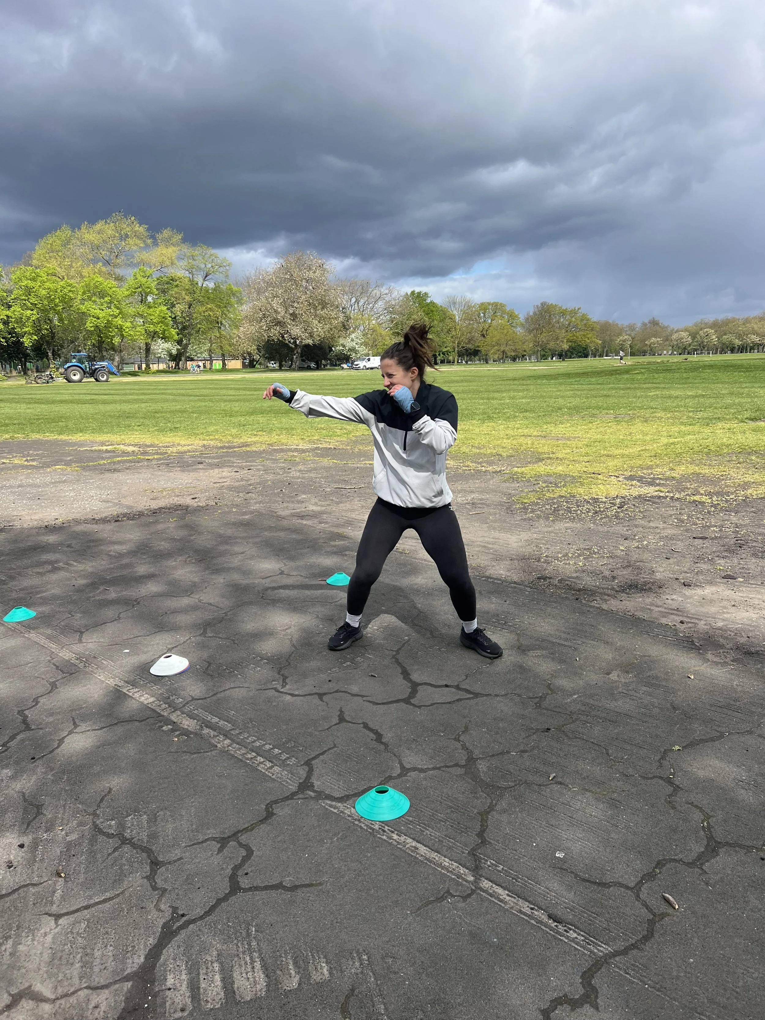 Outdoor boxing training in Victoria Park with coached stance work and open sky at The MAW Studios