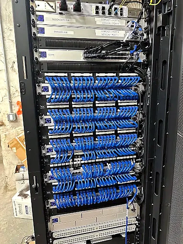 Rack with labeled firewalls, switching, and patch panels installed by Syndonus