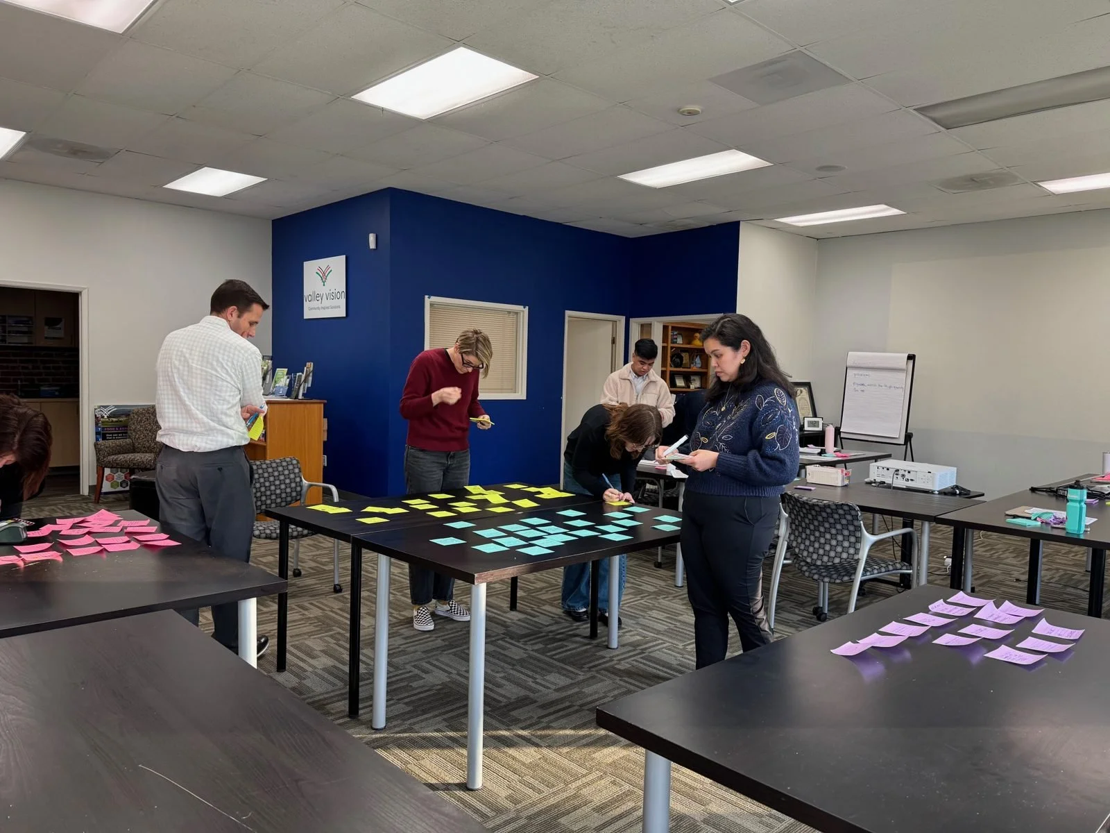Valley Vision staff sorting sticky notes on tables during a working session