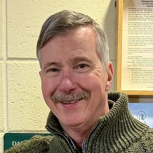 Tom Sparough, smiling, in a green zip-neck sweater.