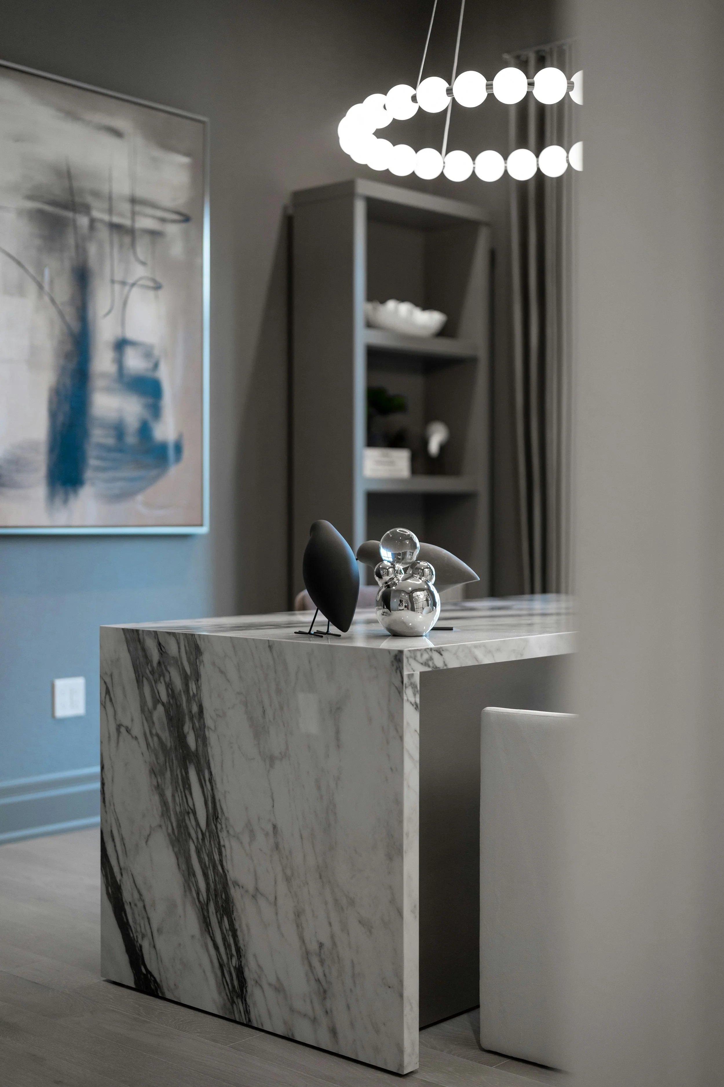 Contemporary interior with a marble table, sculptural lighting, and abstract artwork