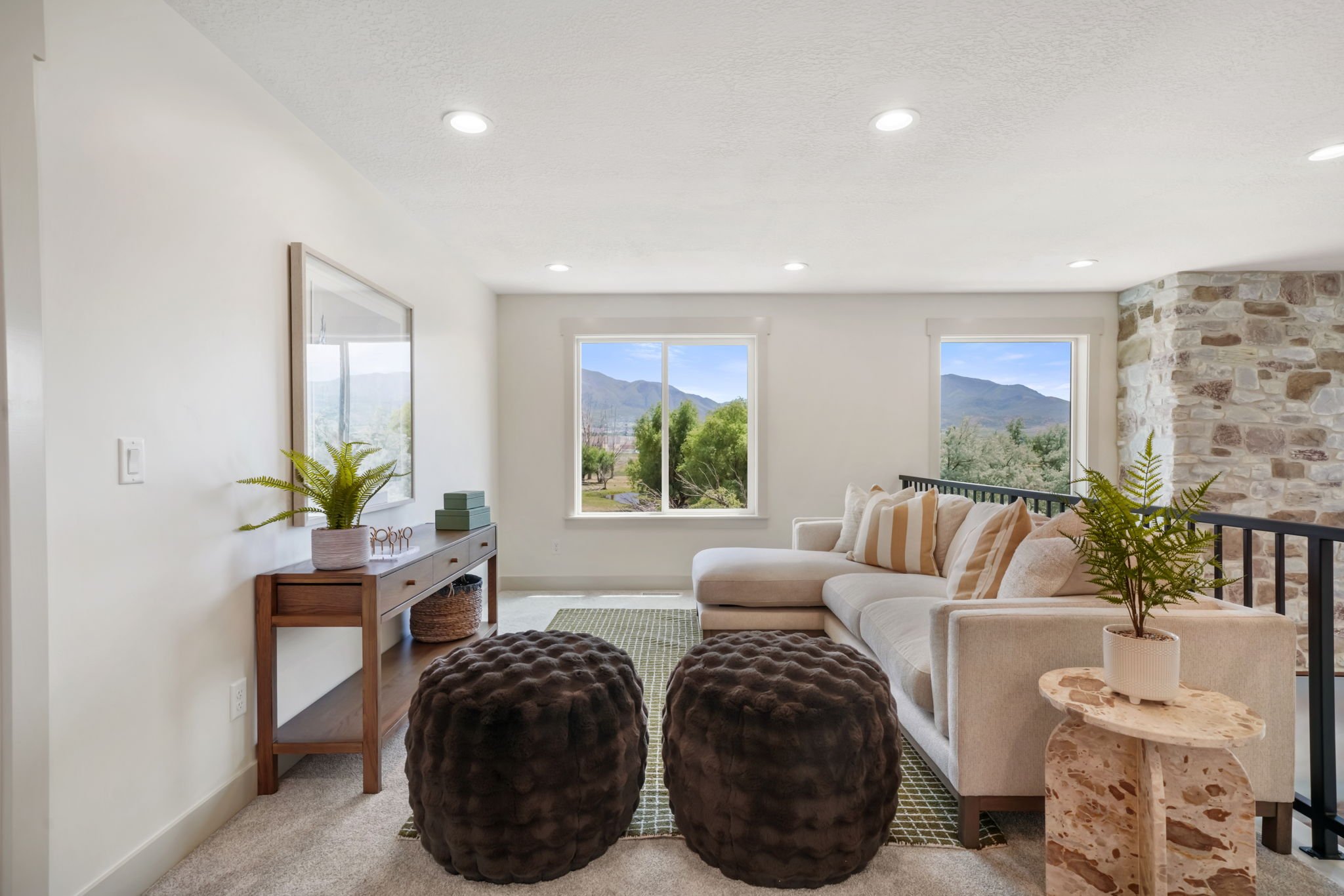 Bright staged living room with a stone accent wall and mountain views through large windows