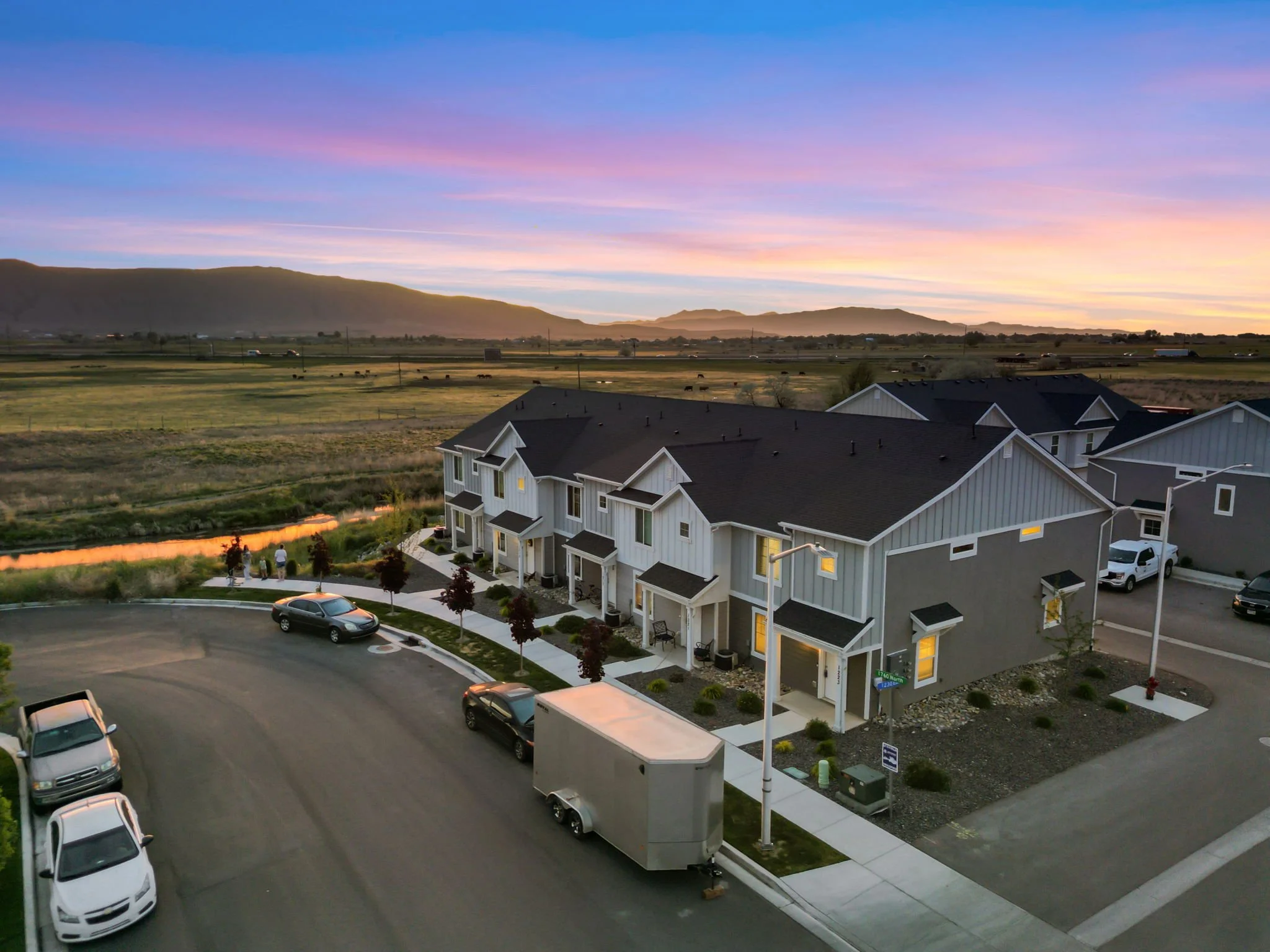 Townhome community at sunset with open land and mountains in the distance