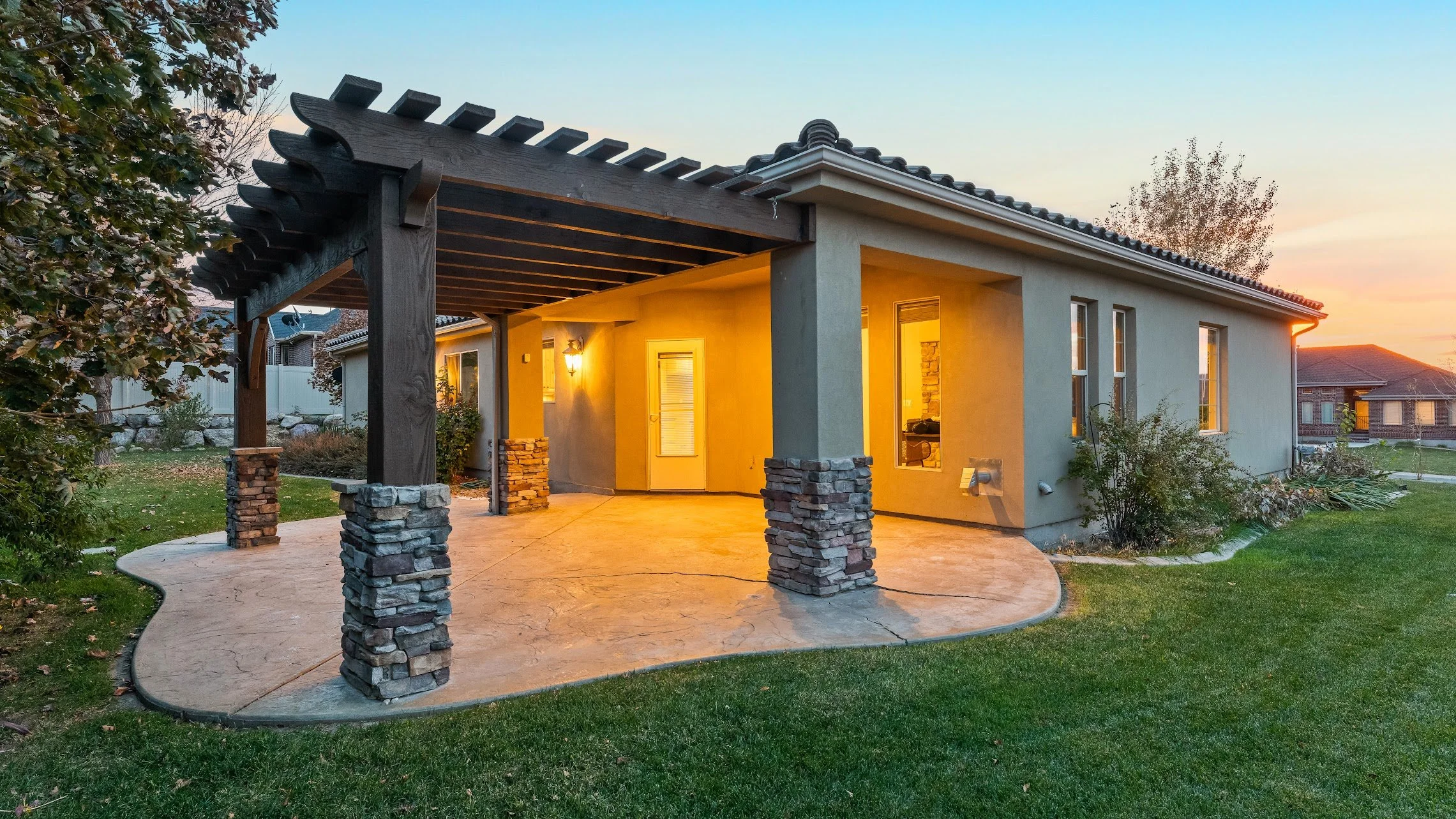 Covered backyard patio with warm evening lighting at a Utah home