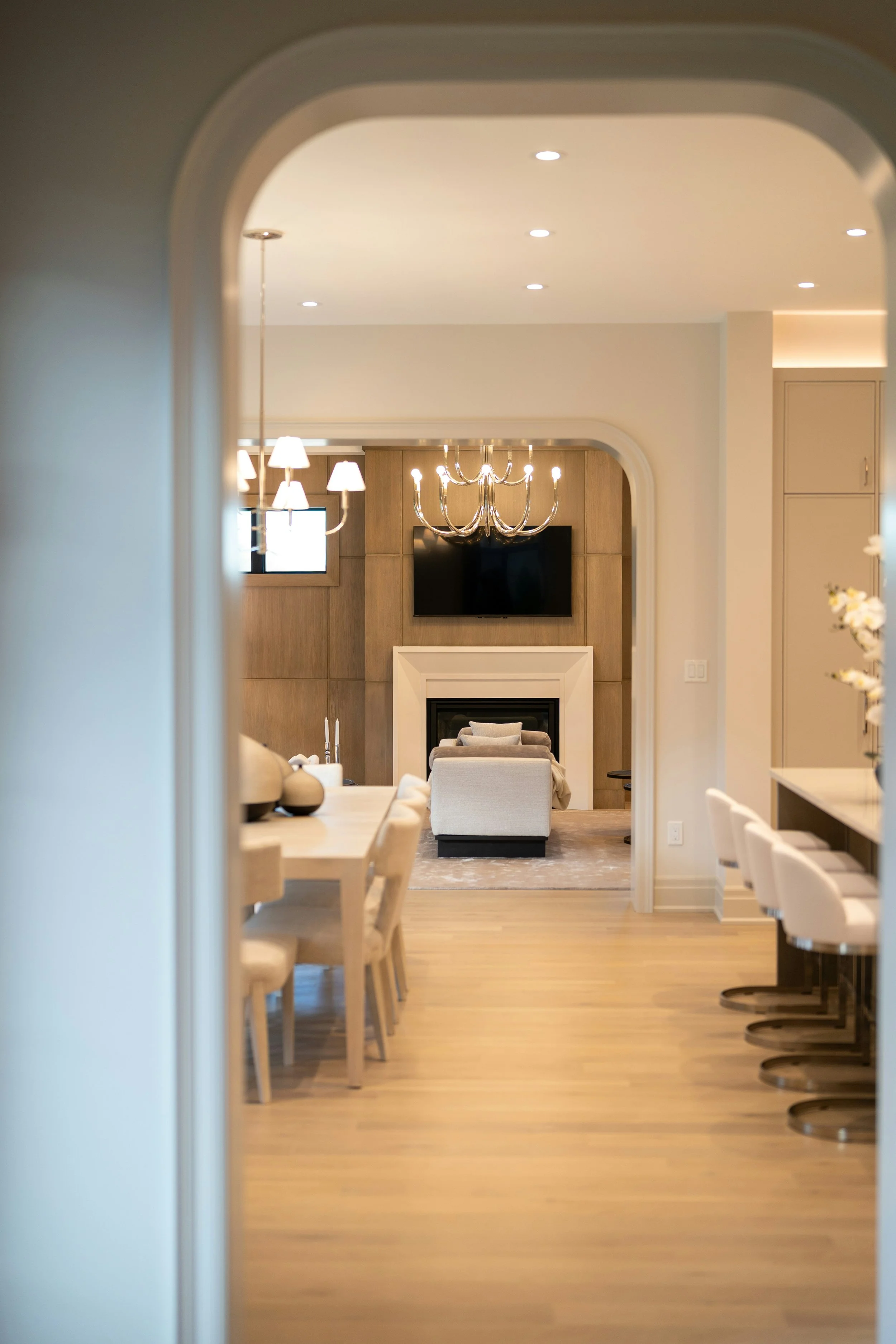 Bright luxury interior framed by a sculptural archway with dining, kitchen, and living spaces