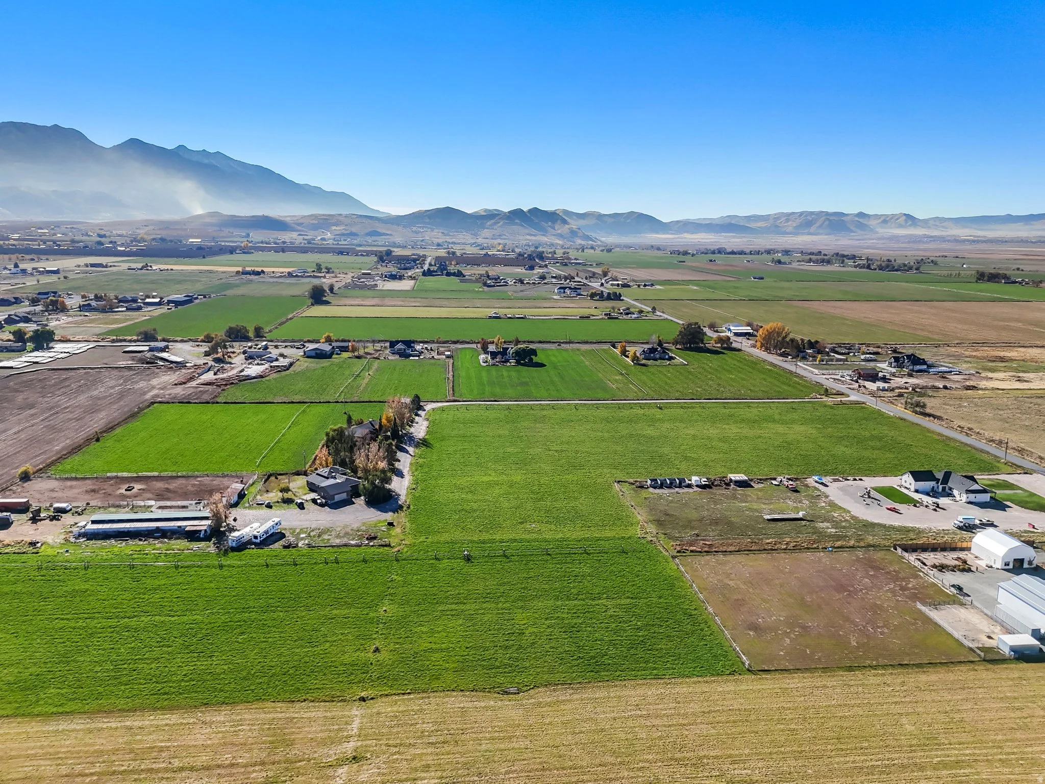 Aerial view of Genola Utah acreage, agricultural fields, homes, and mountain views
