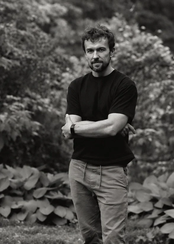 Marcin standing in a garden, arms crossed