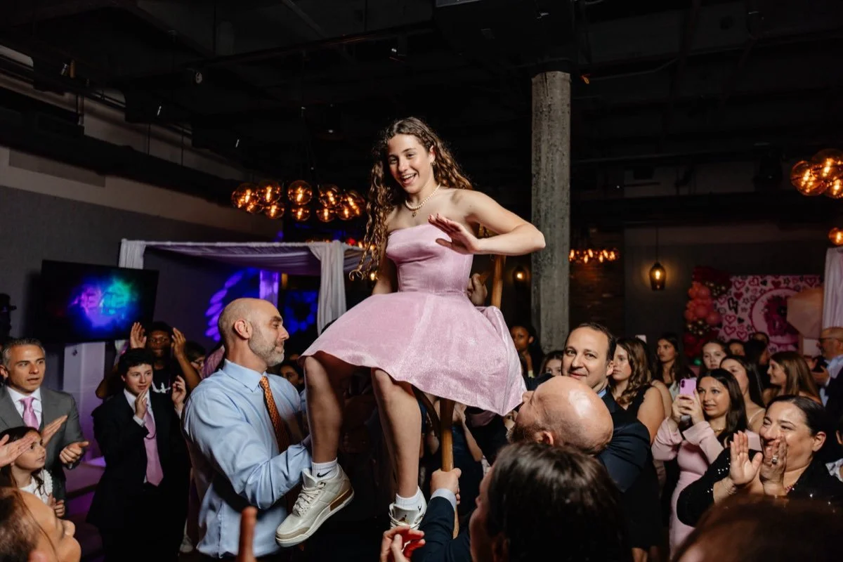 Bat mitzvah celebrant lifted above the crowd during the hora