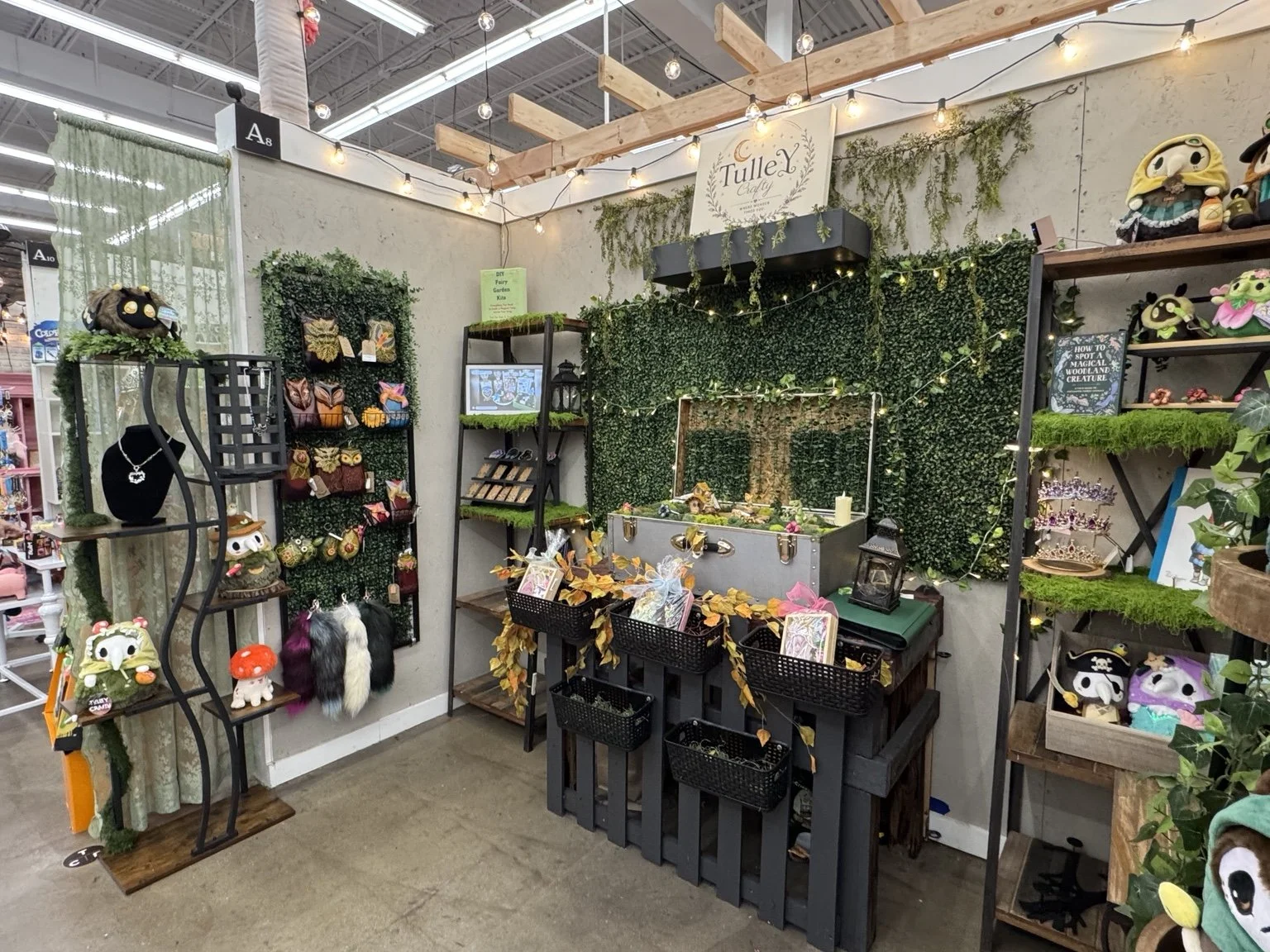 The real TulleY Crafty boutique display inside The Collective Boutiques, with woodland greenery, fairy garden treasures, jewelry, and accessories.