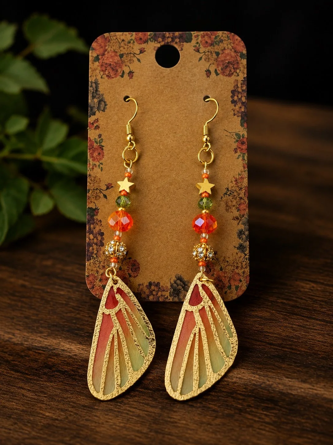 Handmade gold-tone fairy wing earrings with delicate pink and green wings.